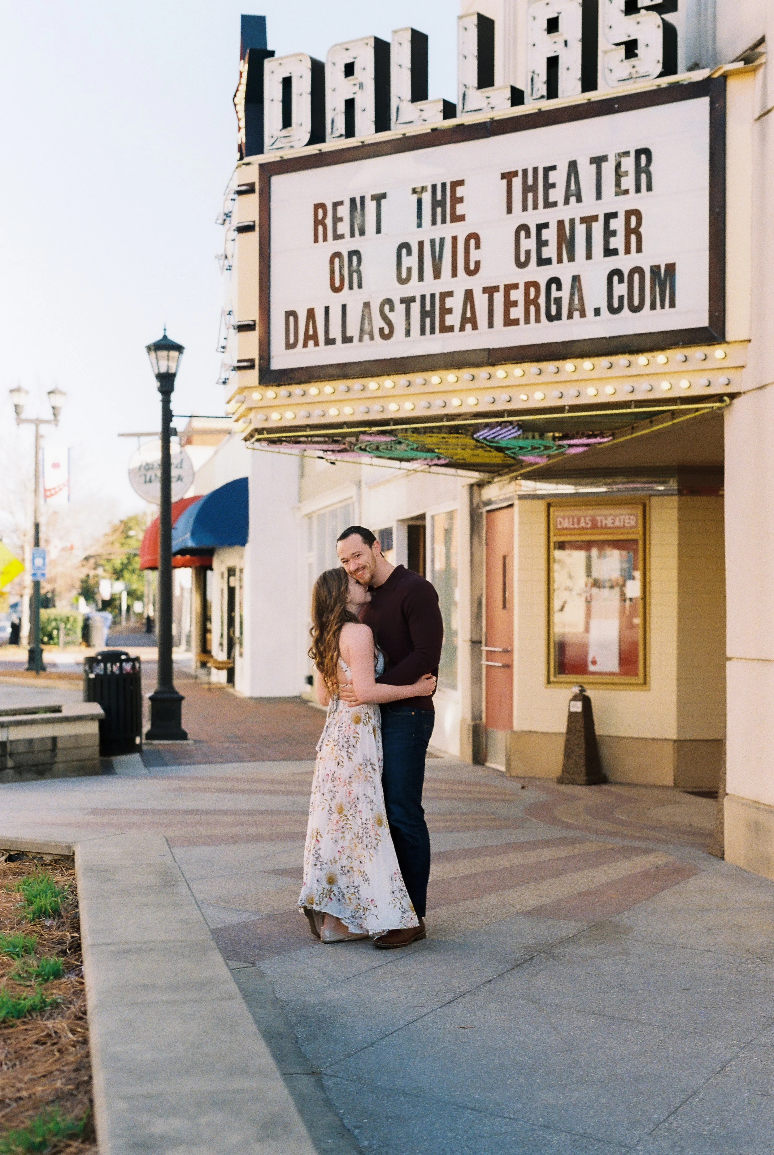 Conner and Maddie stand close together laughing beneath the Dallas Theater marquee in Dallas, Georgia.