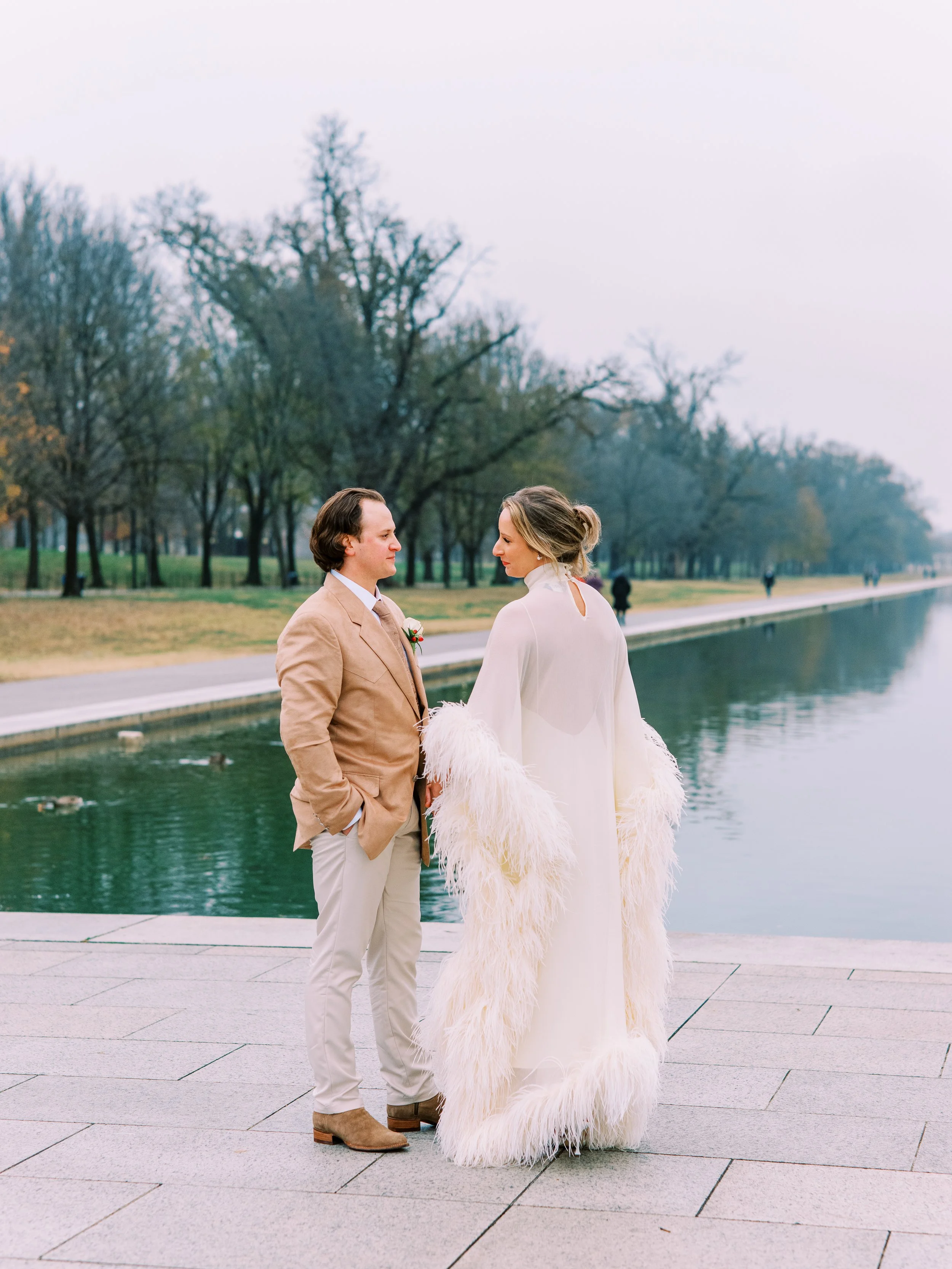 Bride and groom standing together facing each other along the reflecting pool