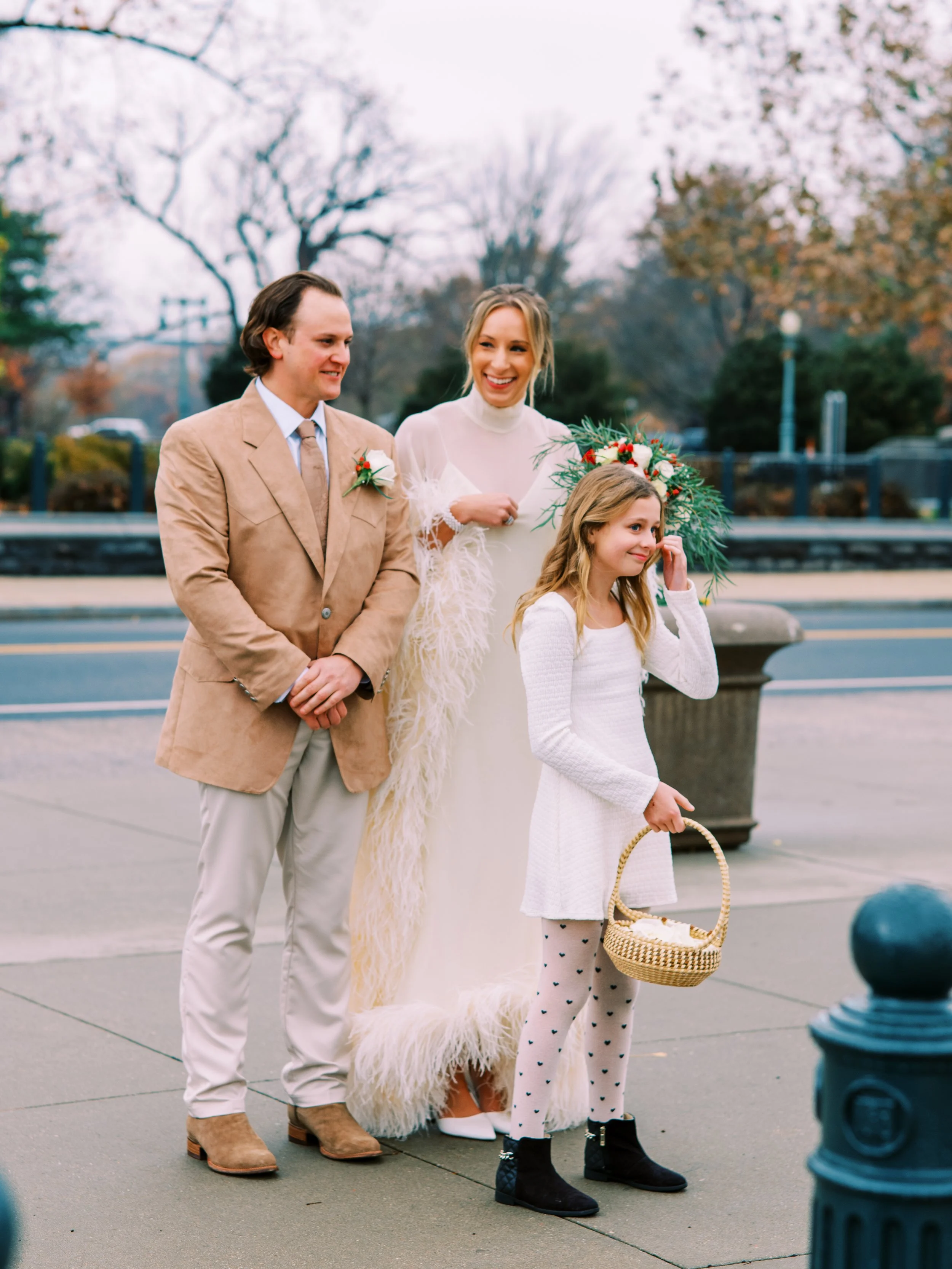 Bride and groom with a flower girl walking together on a city street in Washington DC