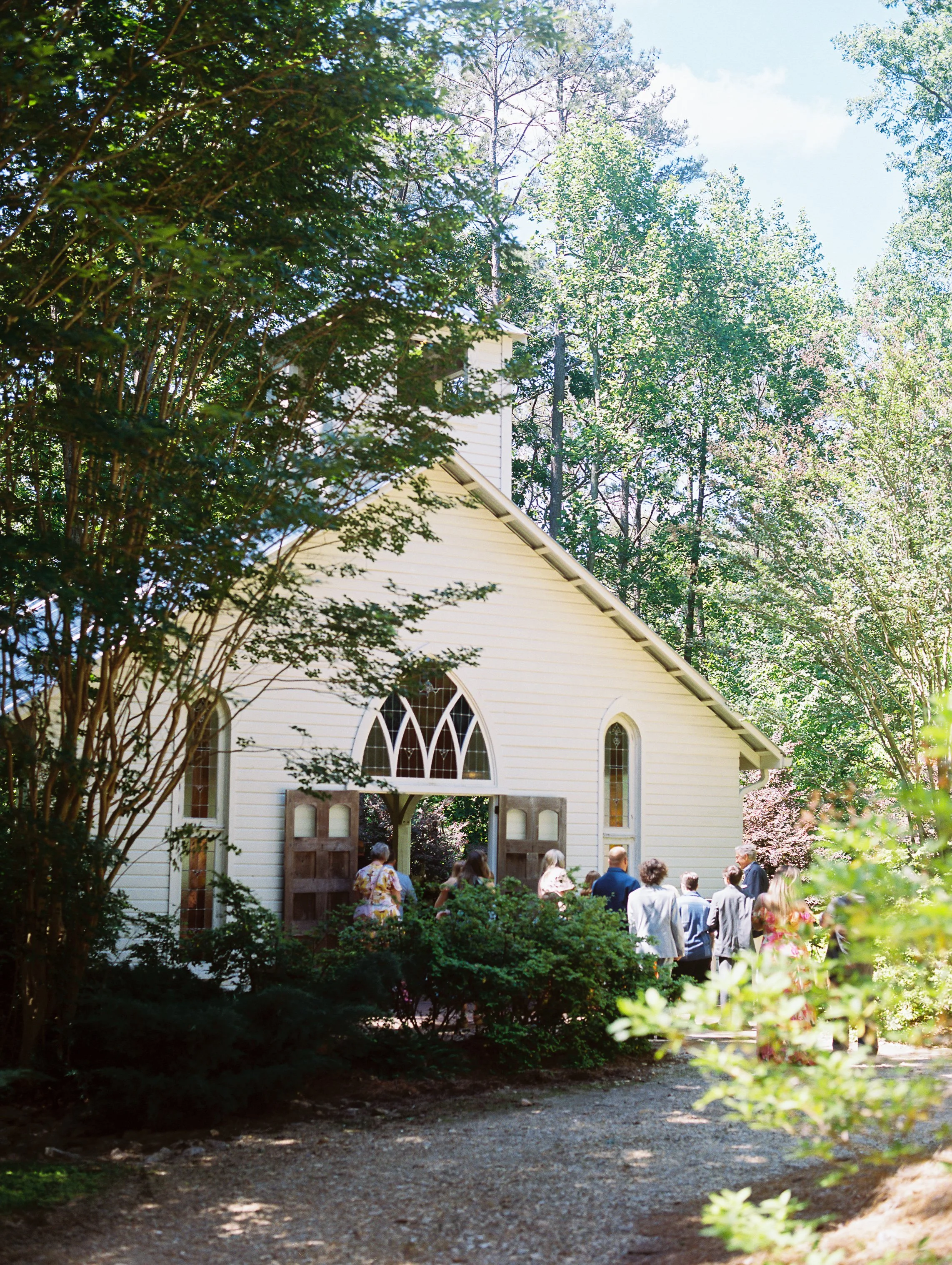 Exterior view of the white chapel with guests arriving for the ceremony