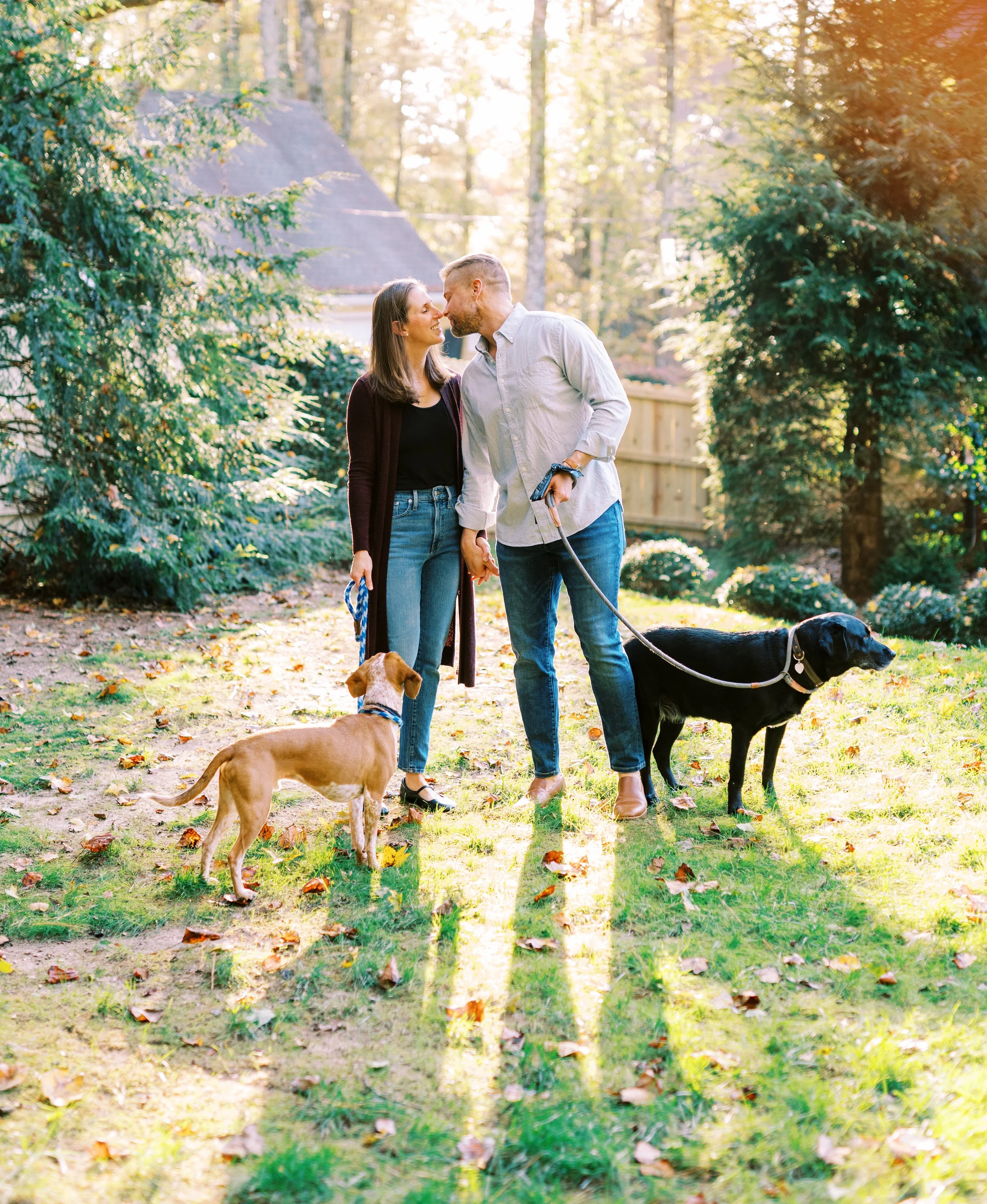 Holly and Chris walking their two rescue dogs together in their wooded backyard in Dunwoody, Georgia