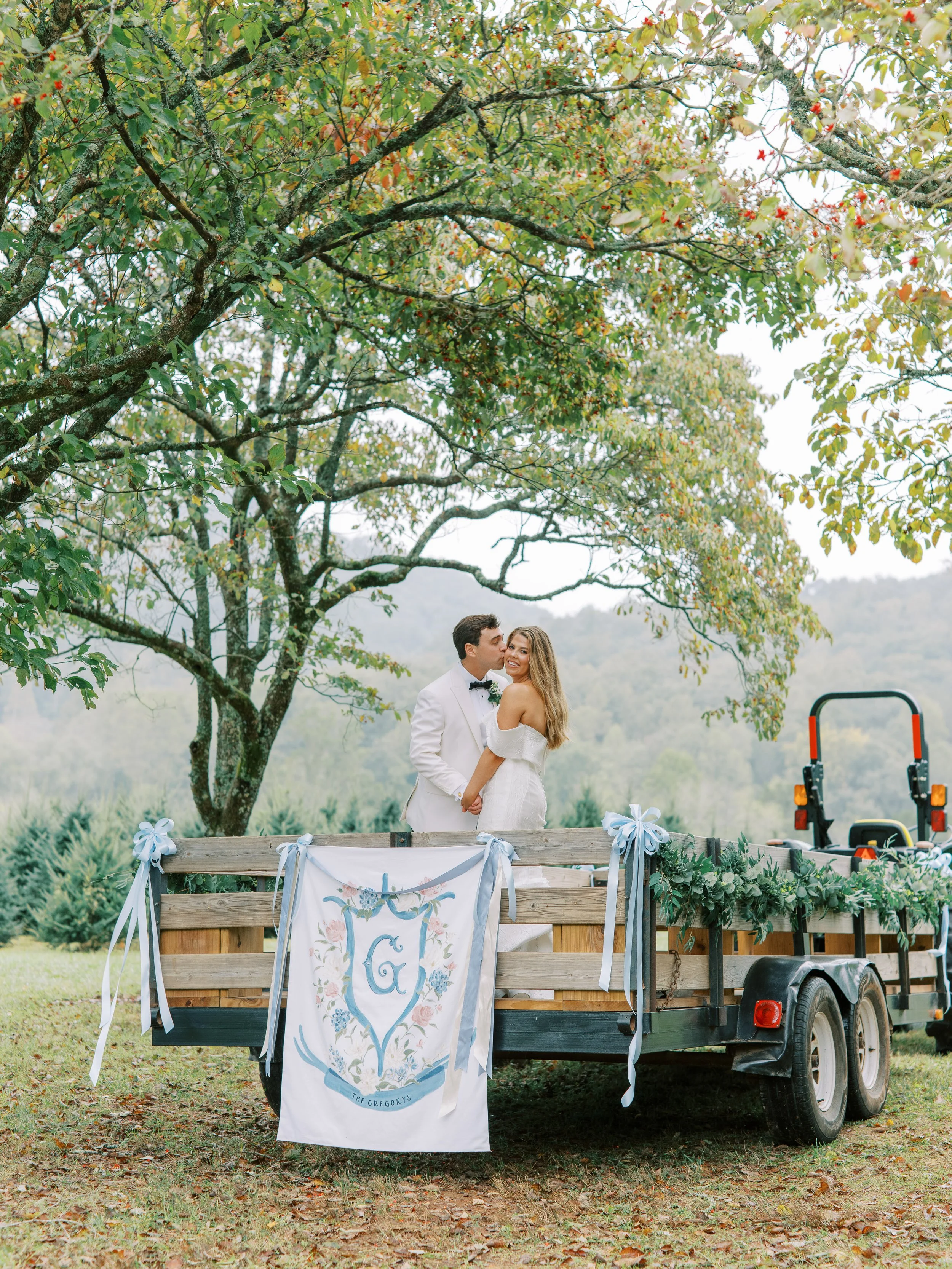 Couple kissing beside the decorated trailer under an autumn tree