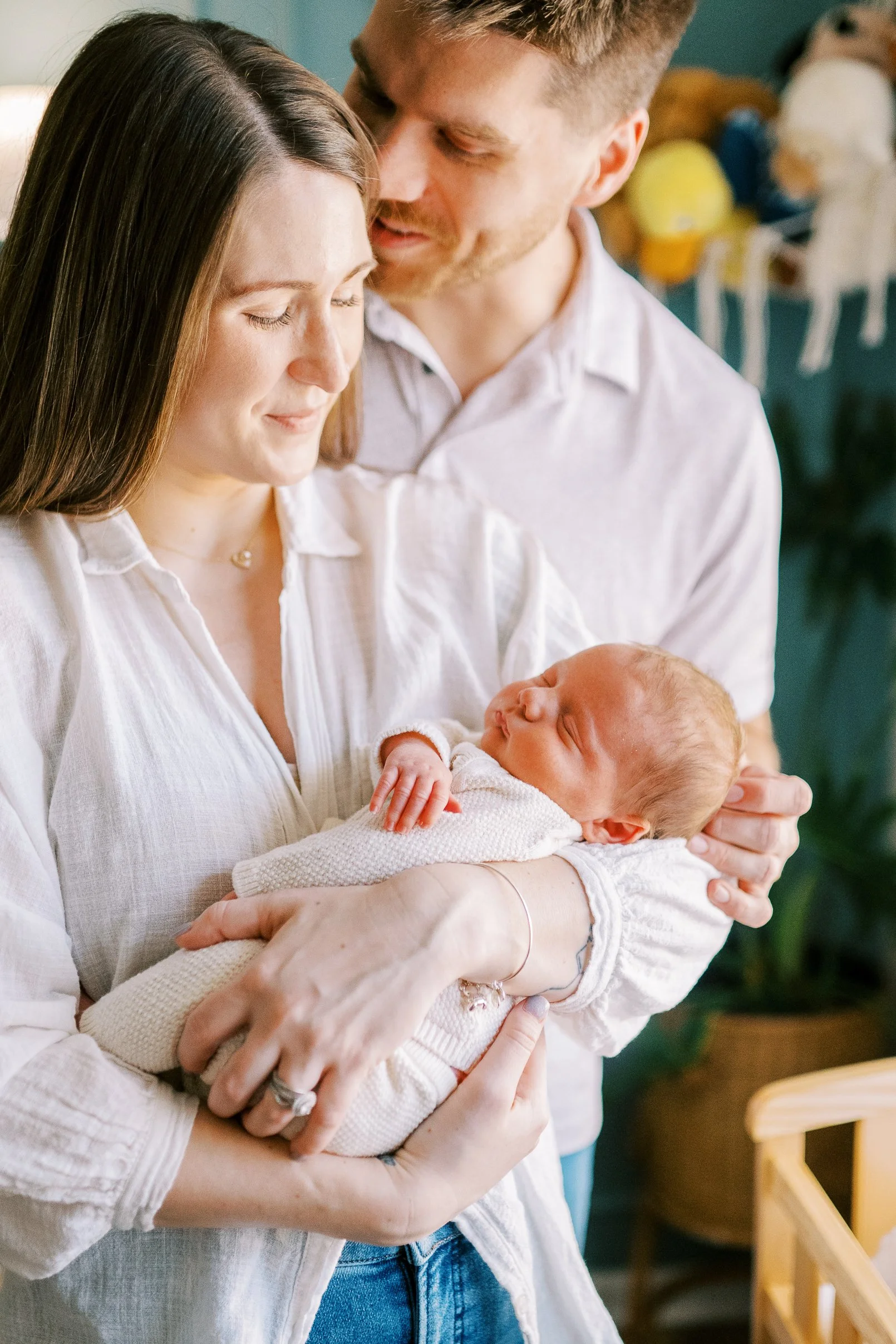 Parents smiling together in the nursery, mom holding their newborn baby, Roswell, Georgia