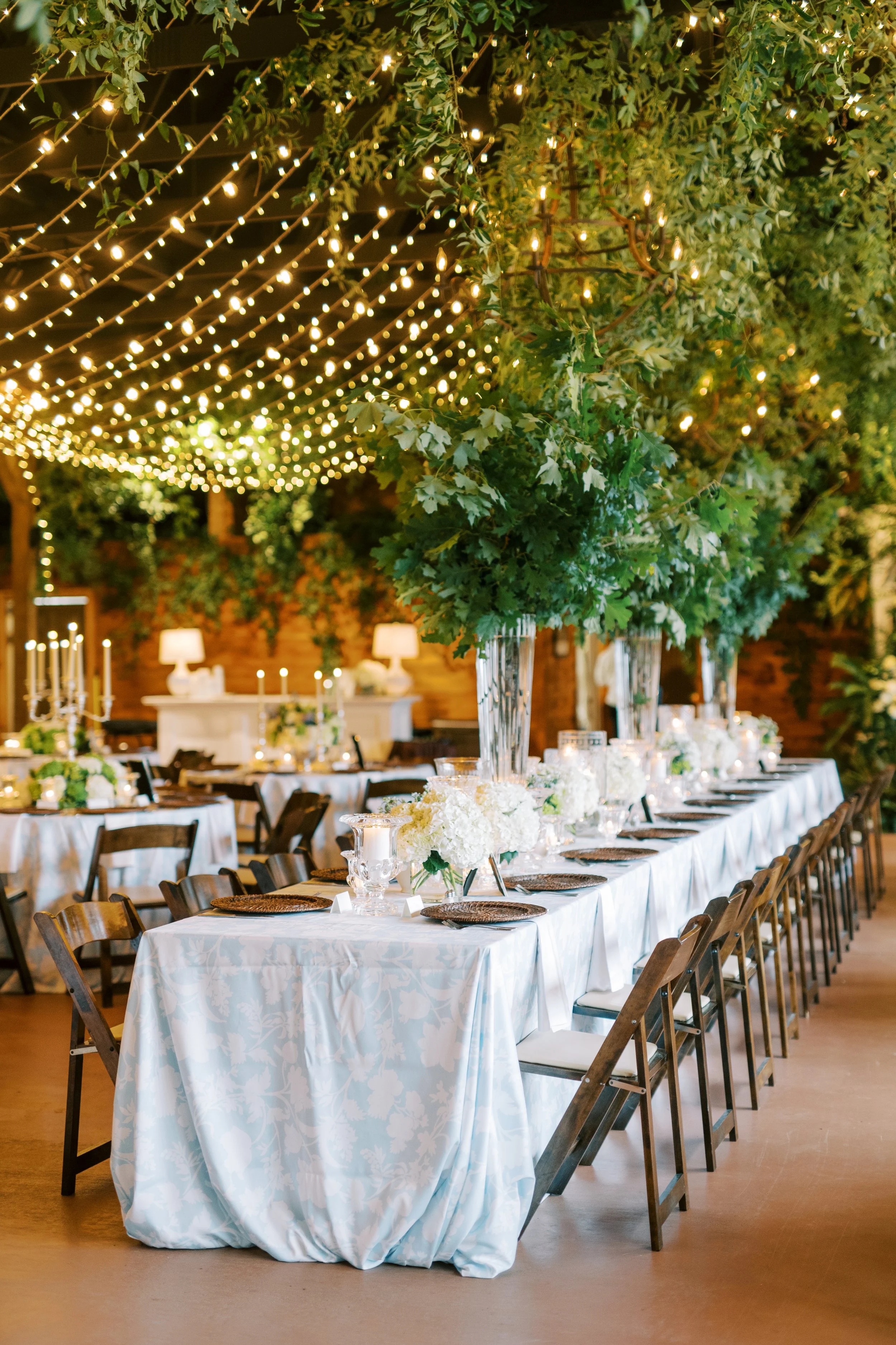 Long banquet reception table set outdoors beneath string lights