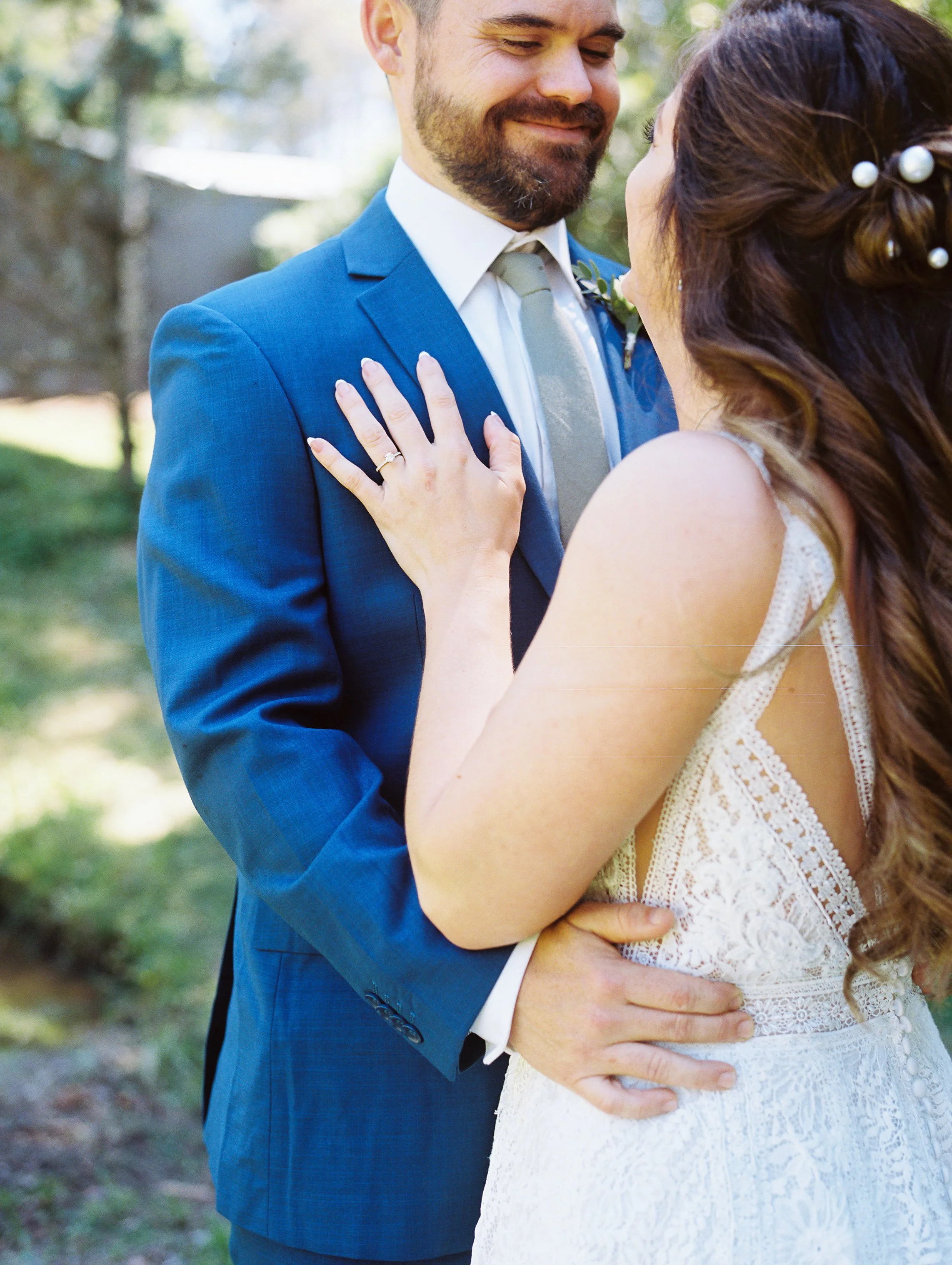 Groom smiling down at the bride with his hand on her waist as she rests her hand on his chest, close embrace