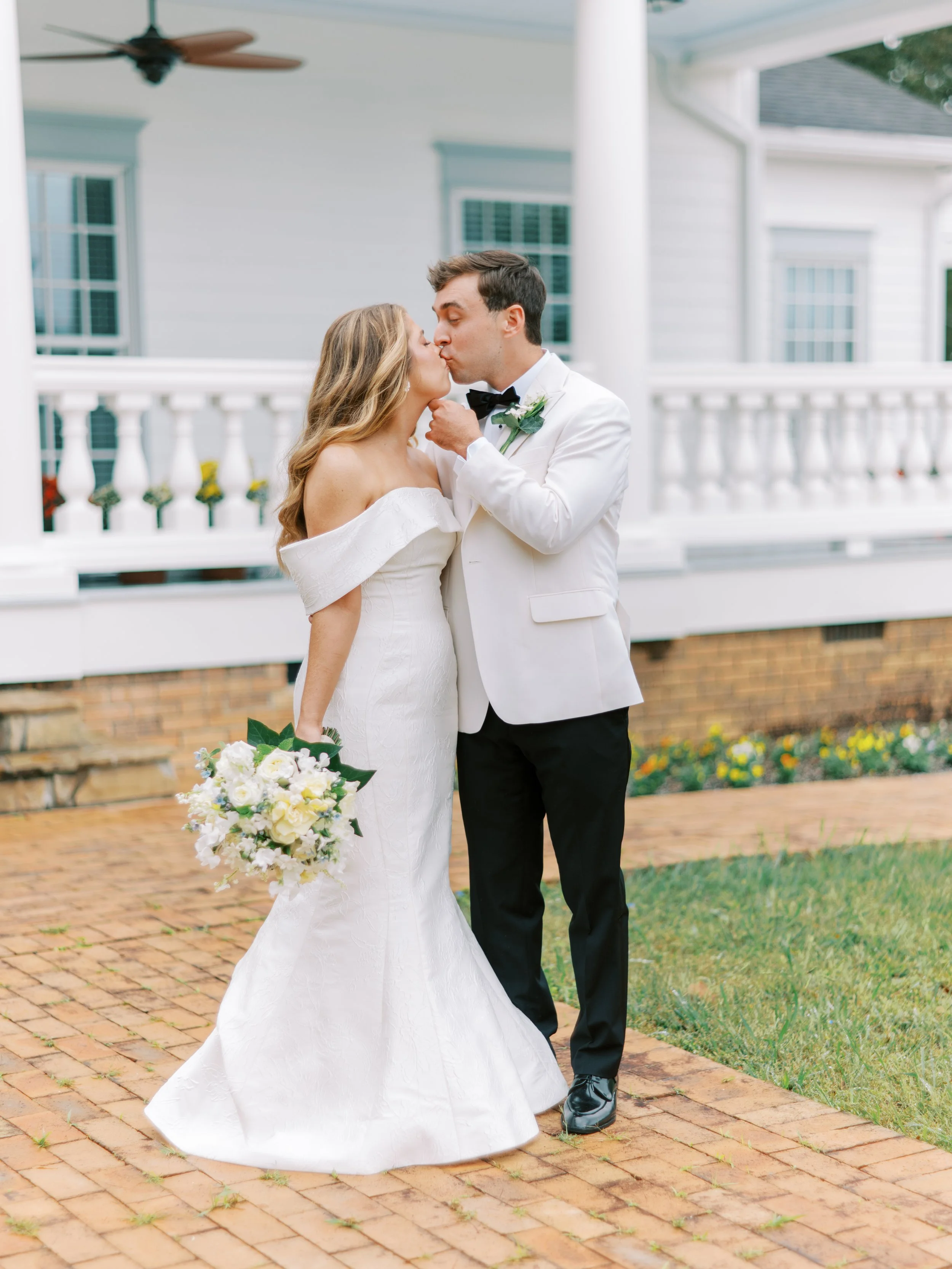 Groom kissing the bride's forehead on the plantation house porch