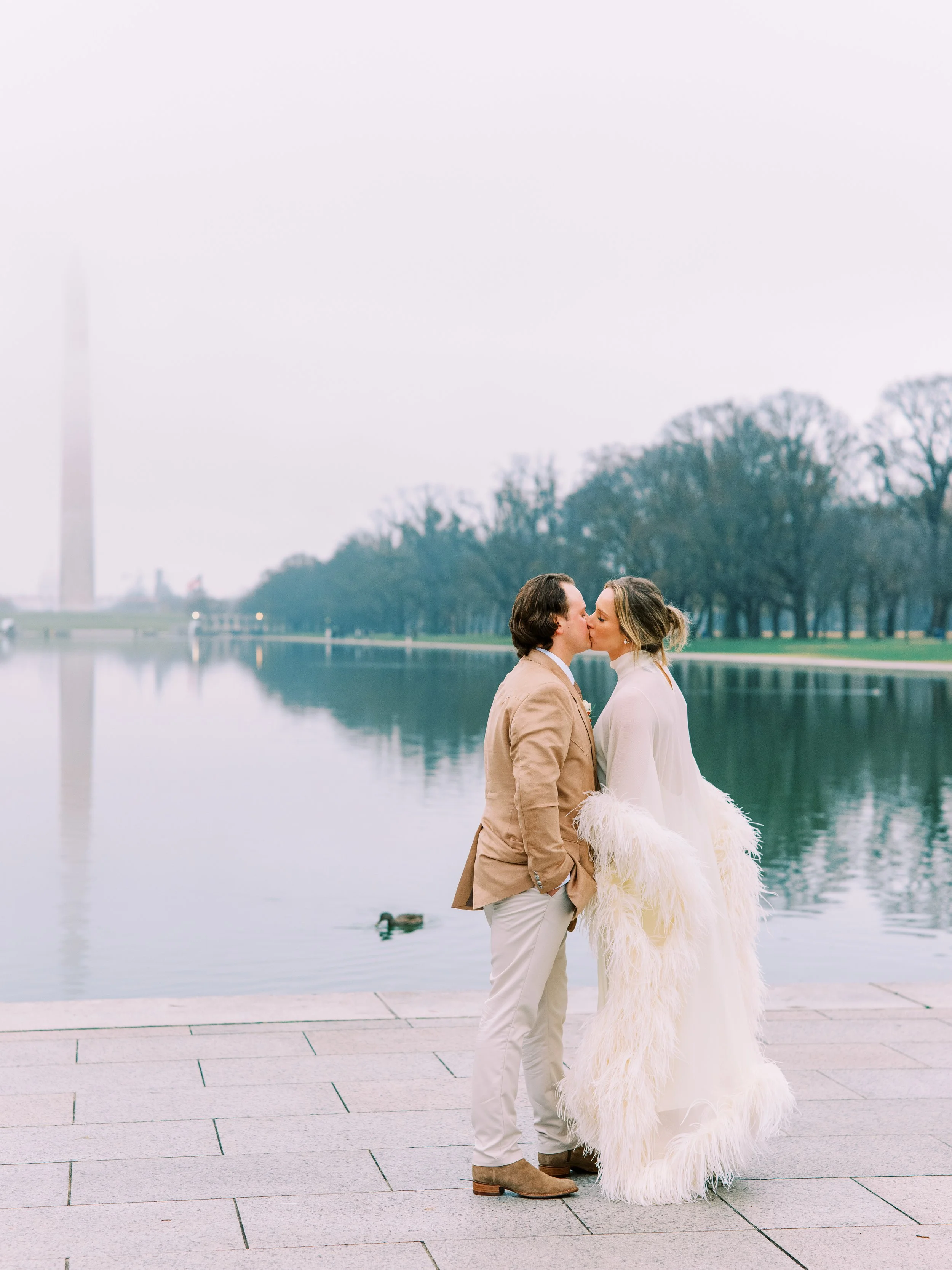 Bride and groom kissing beside the reflecting pool with the Washington Monument in view