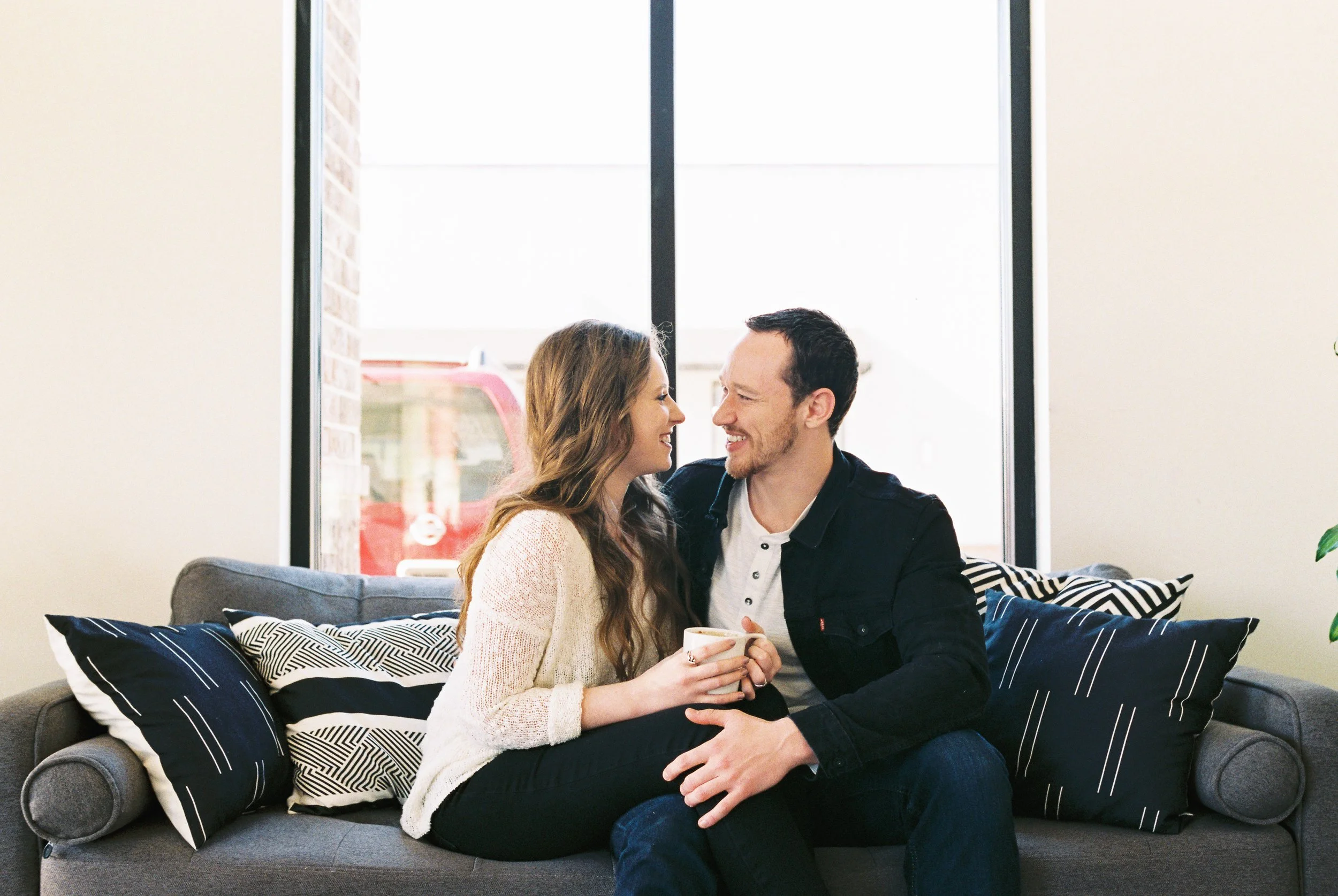 Conner and Maddie share a laugh on a couch by a large window in a Dallas, Georgia coffee shop.