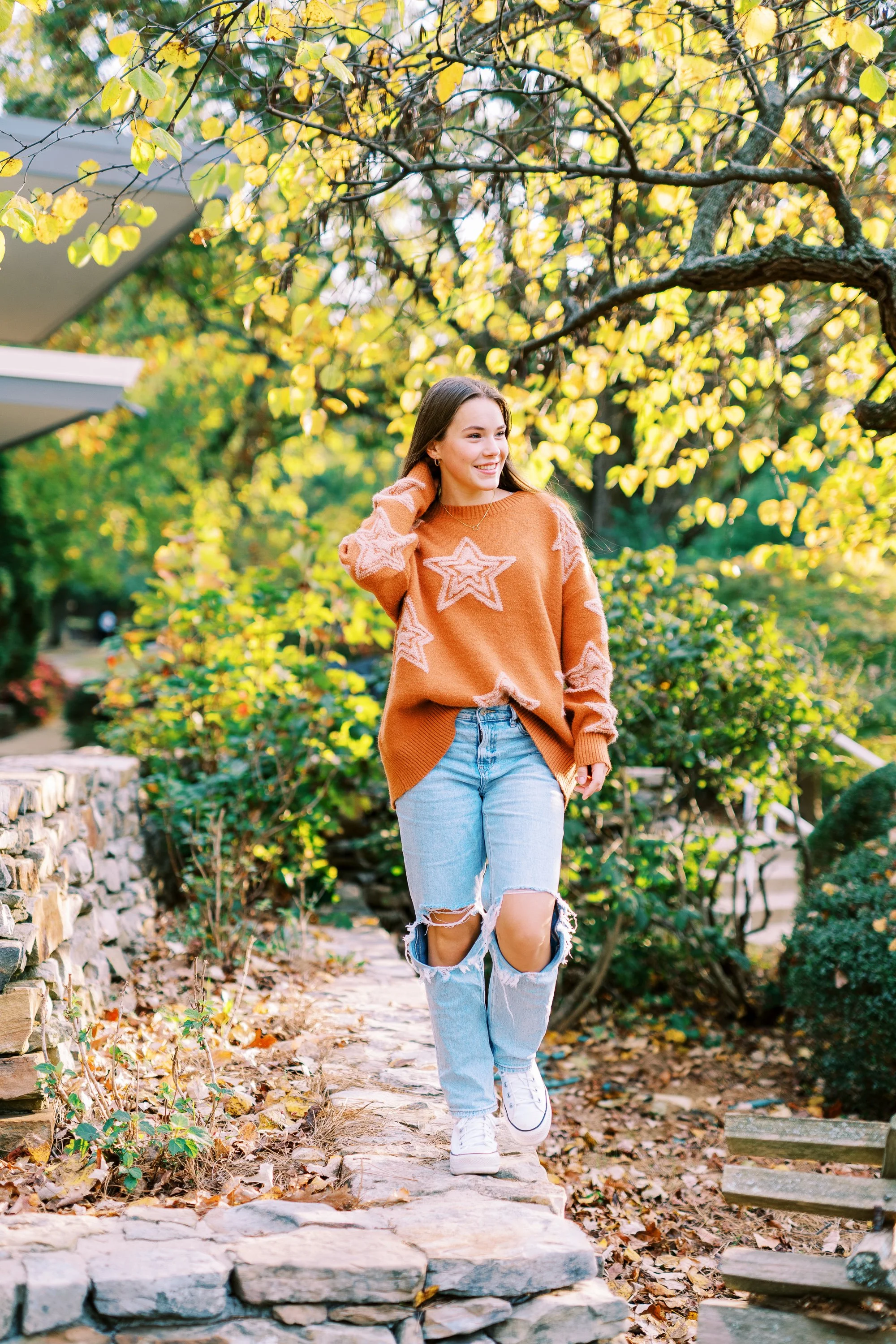 Senior portrait of Hannah standing on stone steps in an orange sweater at Kennesaw Mountain Battlefield Park in Kennesaw, Georgia