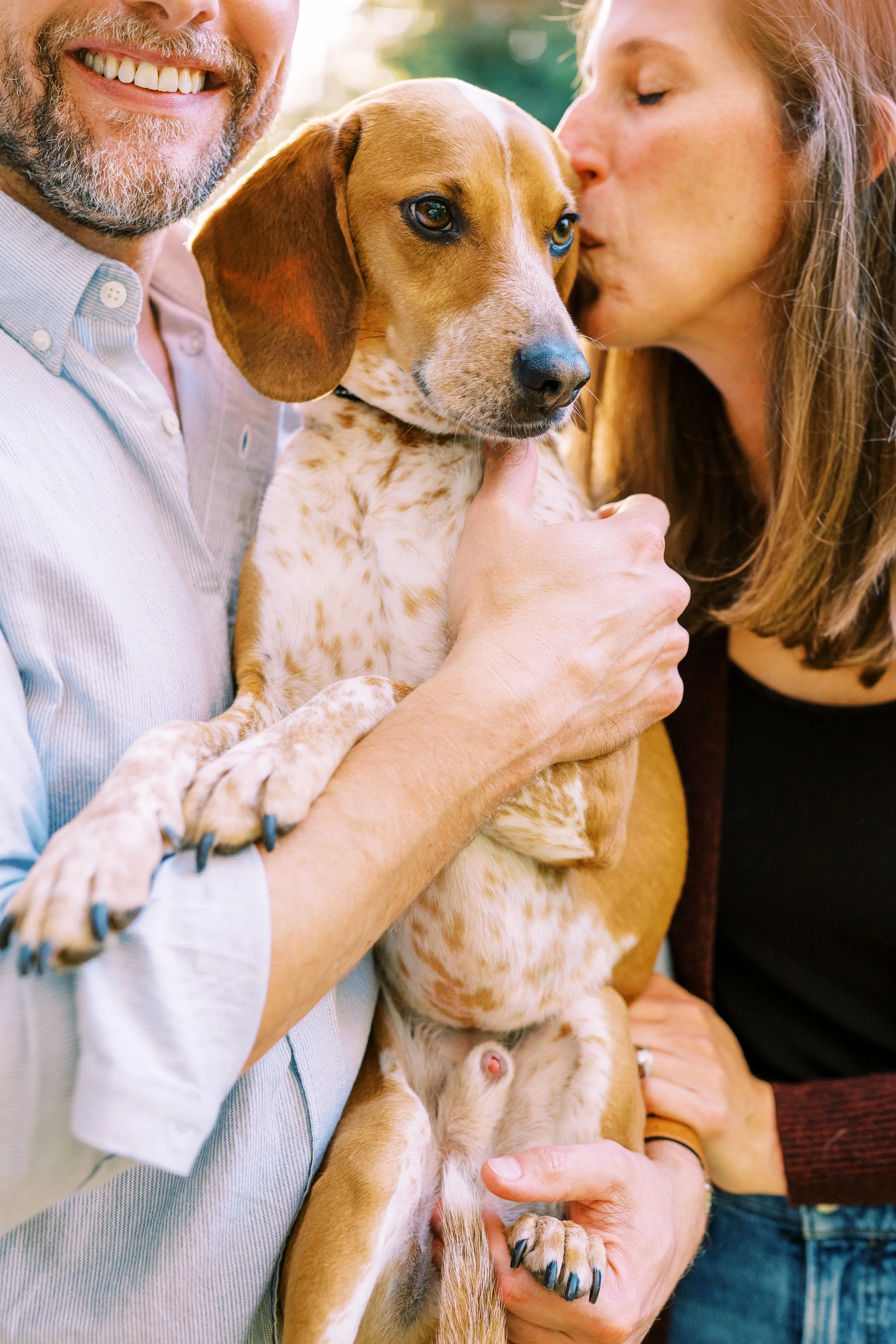 Close-up of Holly and Chris cuddling and kissing one of their rescue dogs