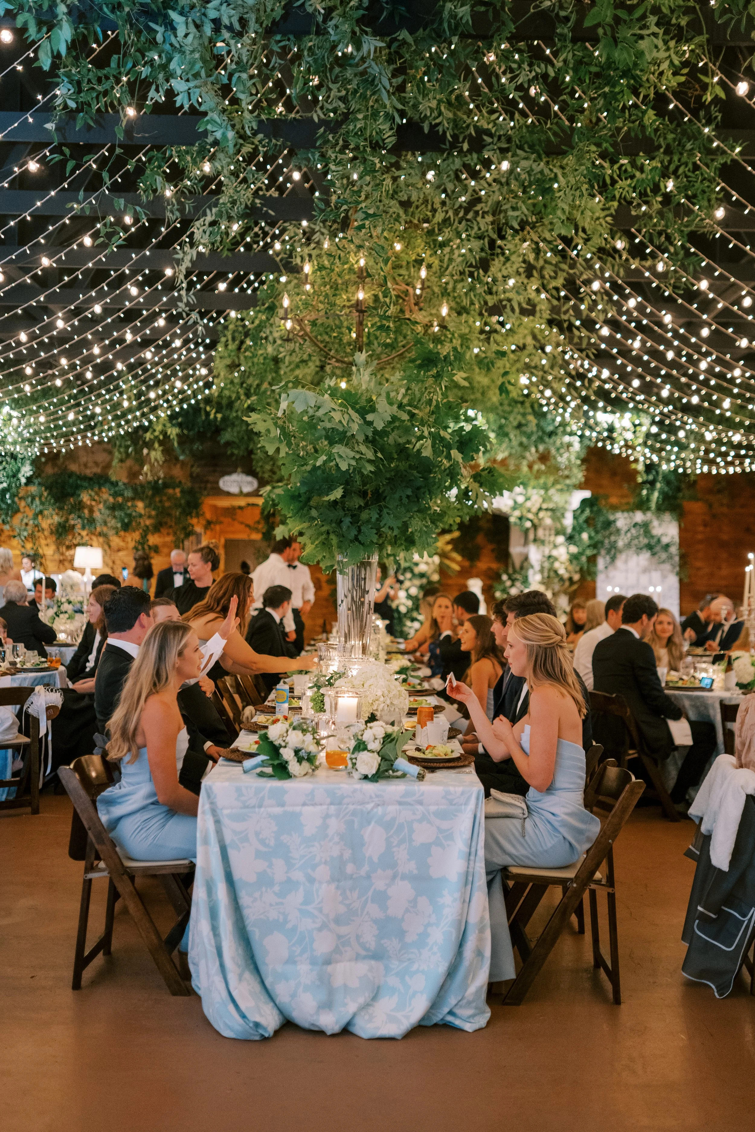 Wide view of reception venue with seated guests and blue-linen head table