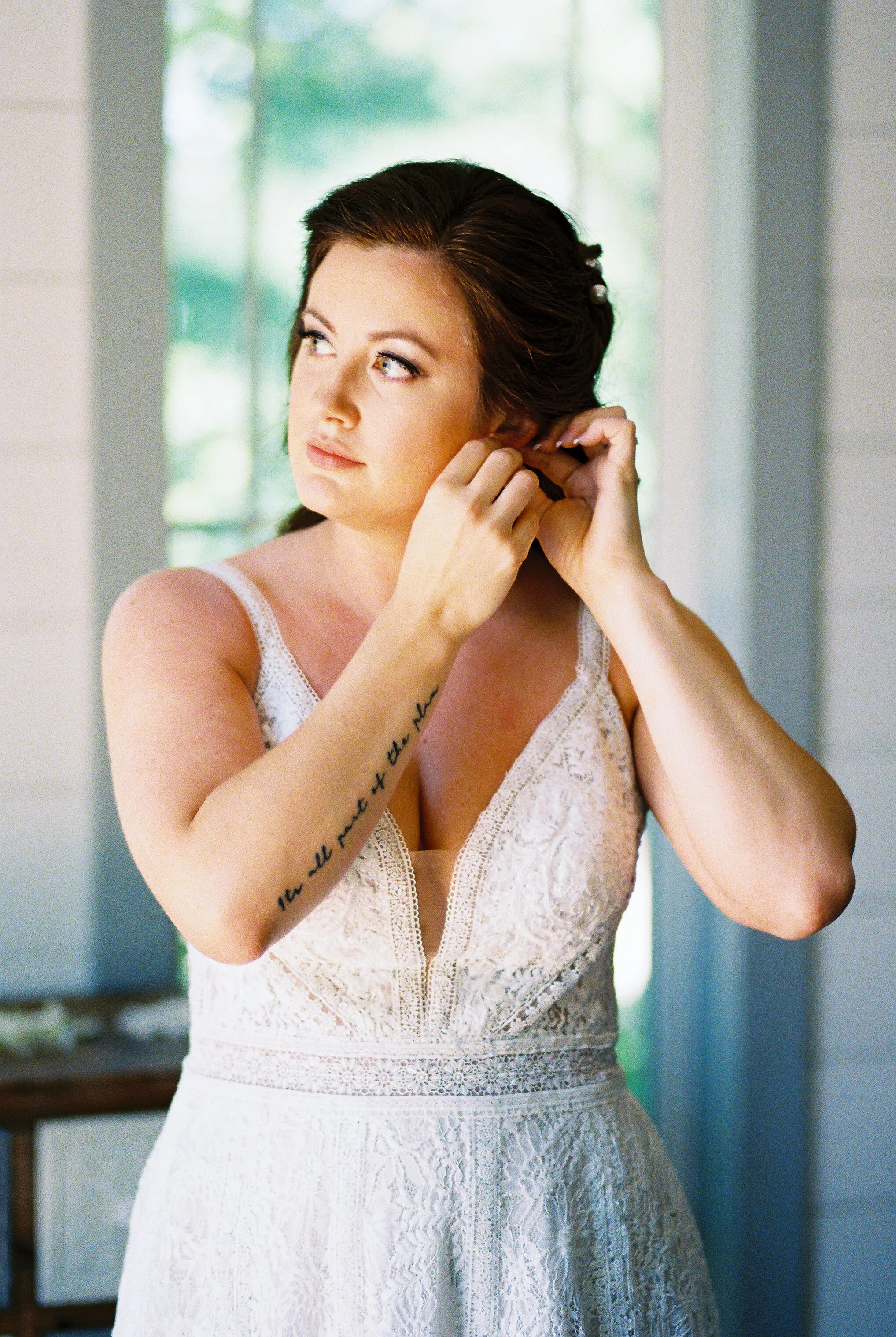 Bride putting on earrings while getting ready before her Muse Farms wedding