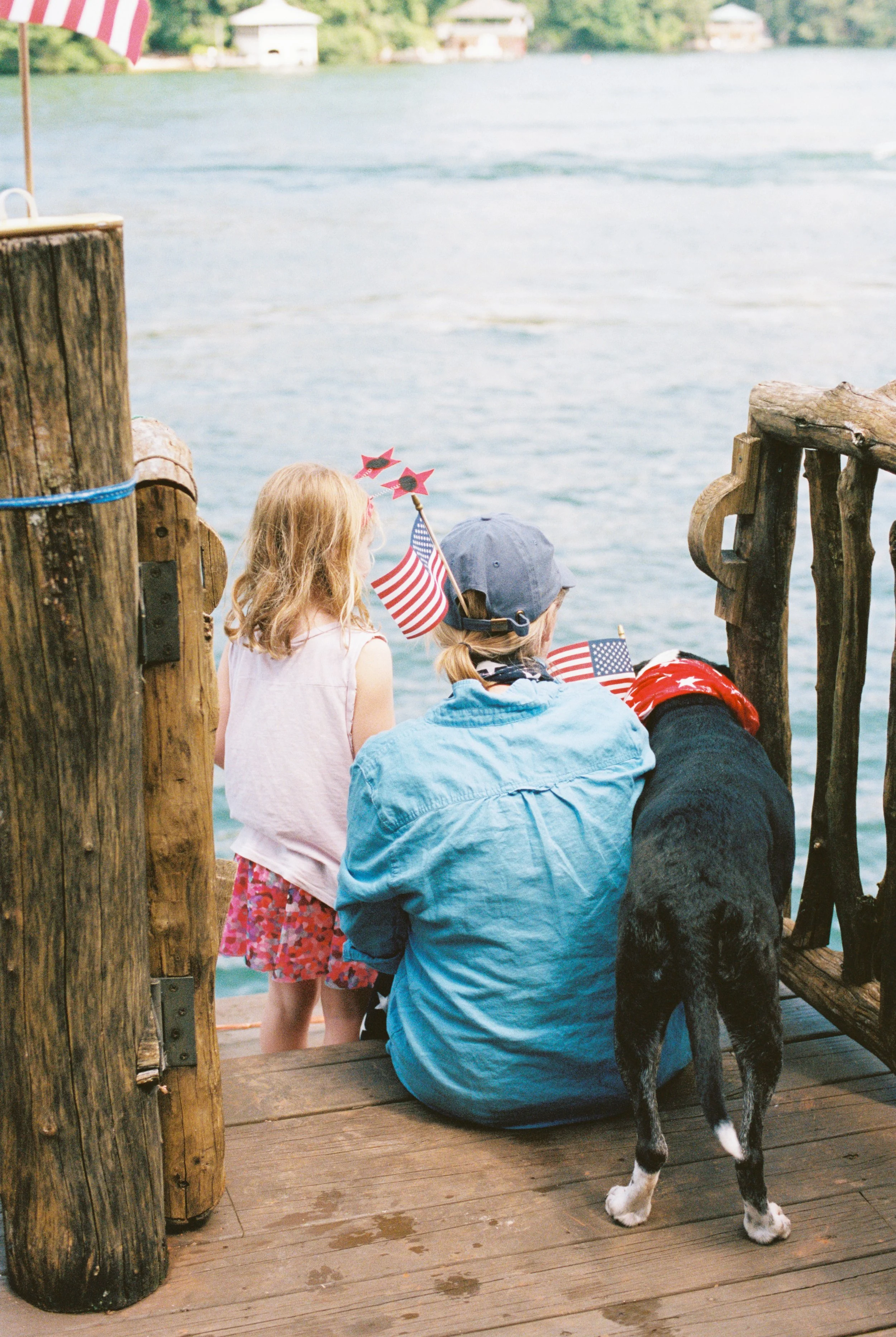 Family sitting together on the dock with their dog, looking out over Lake Rabun