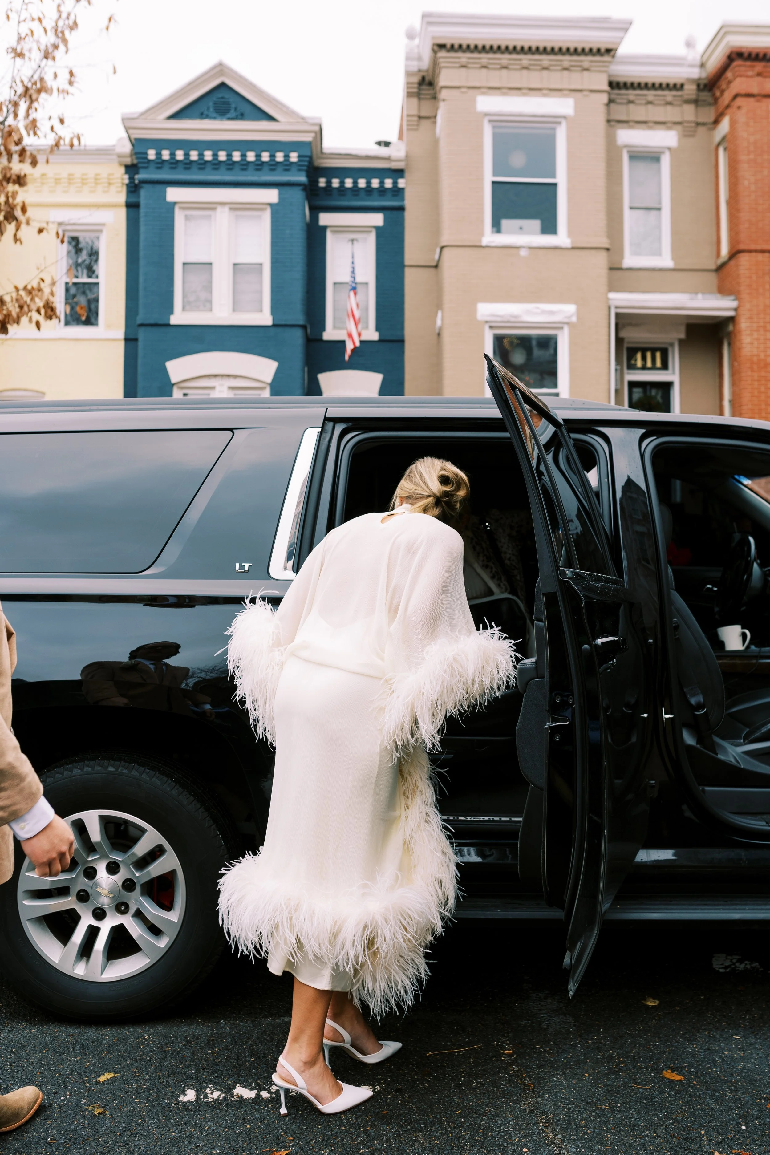 Bride in her fur coat entering a car on a Washington DC city street