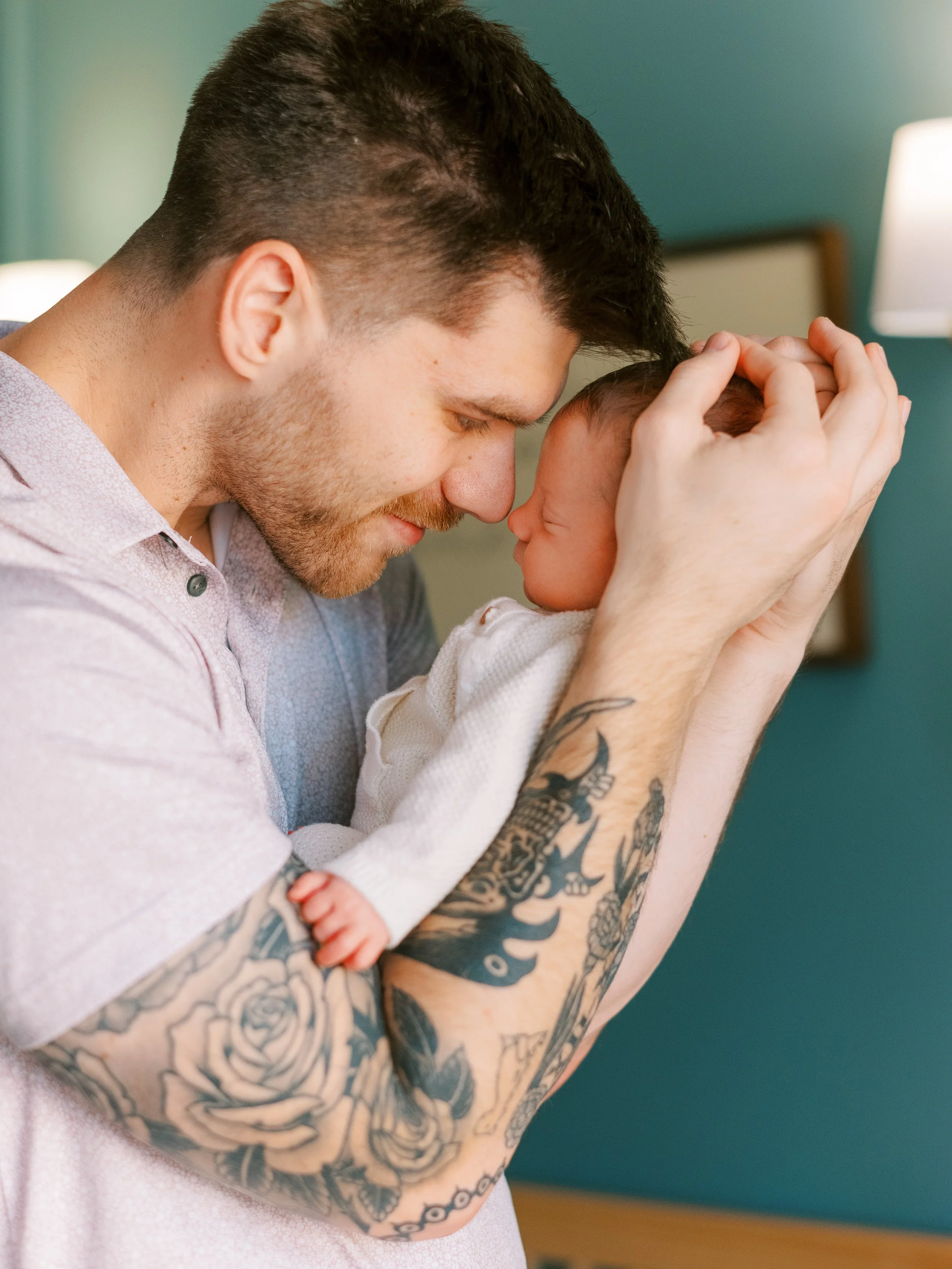 Newborn baby cradled in dad's arms with mom's hands resting gently beside him, Roswell, Georgia