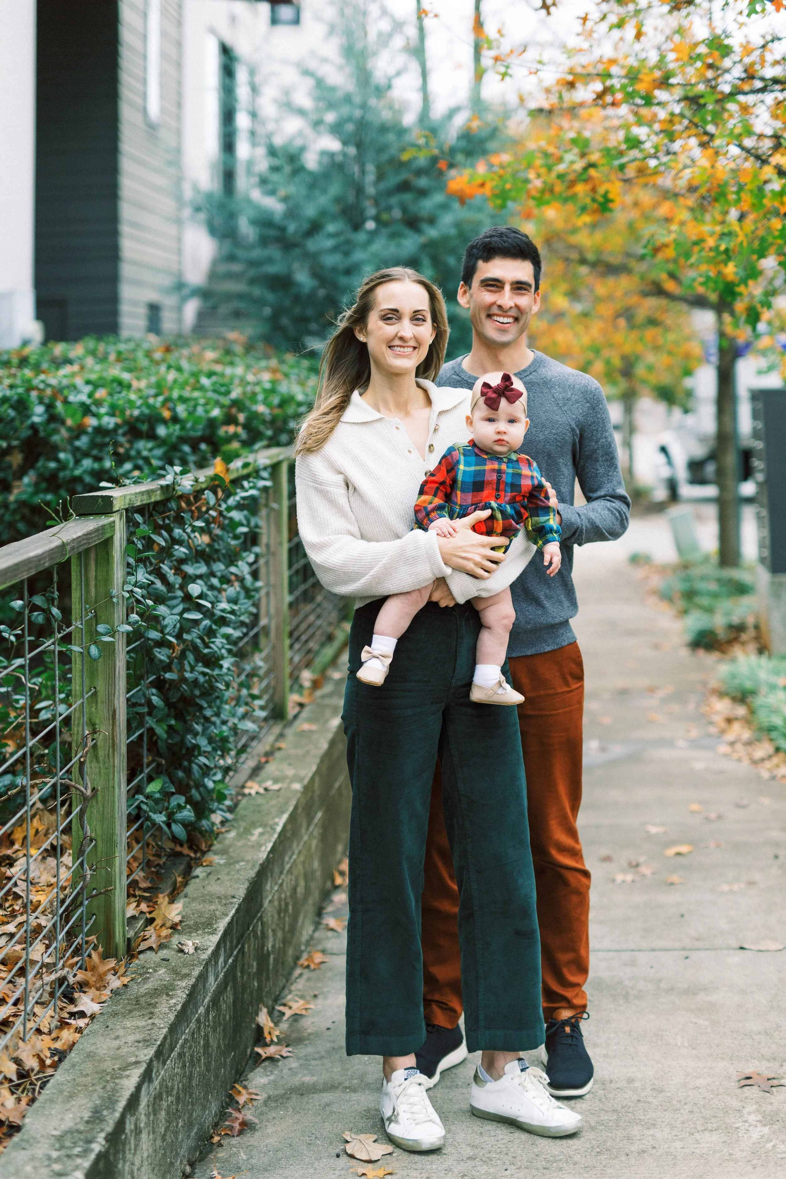Parents sharing a kiss while holding their baby girl outdoors in the fall, Reynoldstown, Atlanta, Georgia