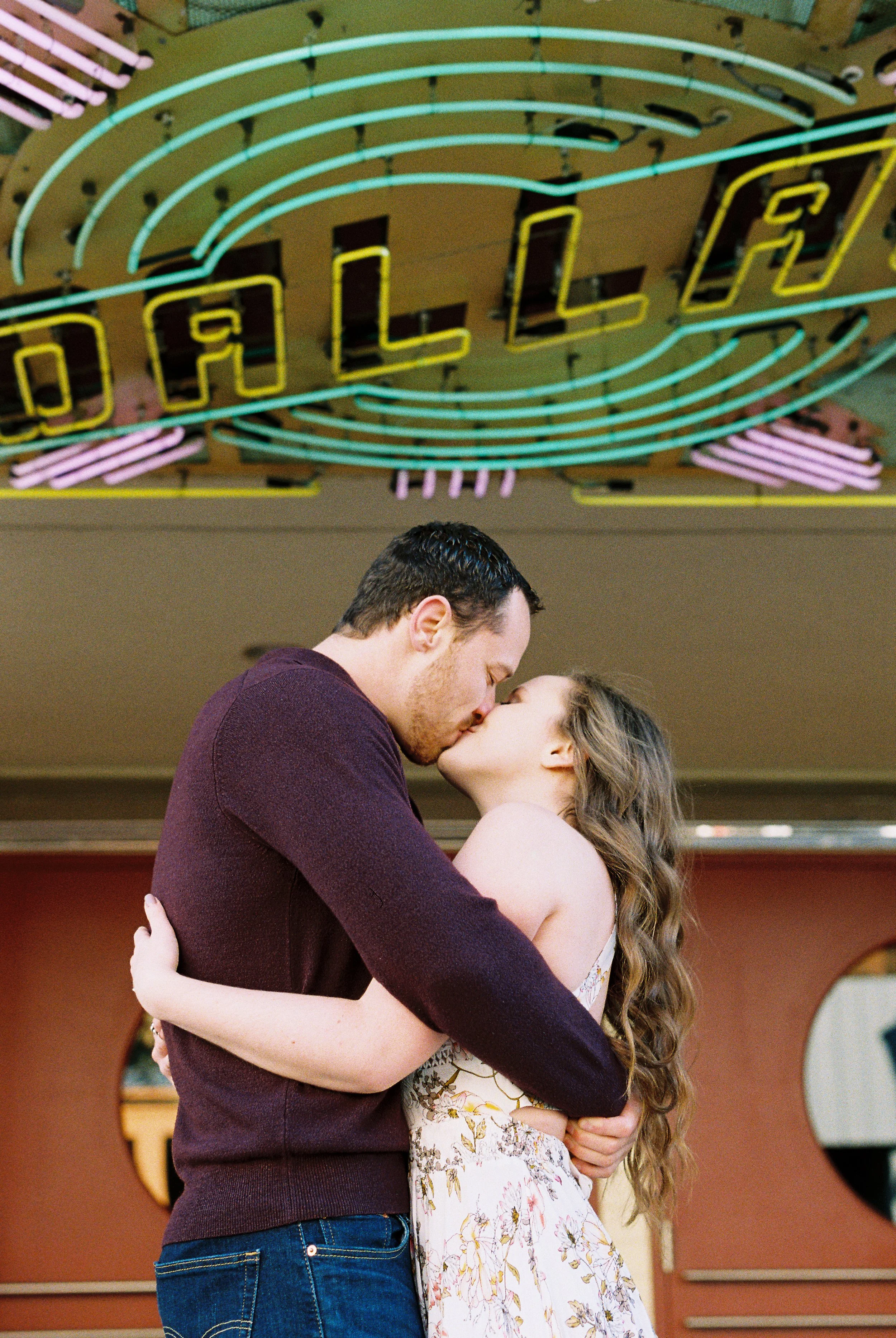 Conner and Maddie kiss beneath the illuminated neon Dallas Theater sign in Dallas, Georgia.