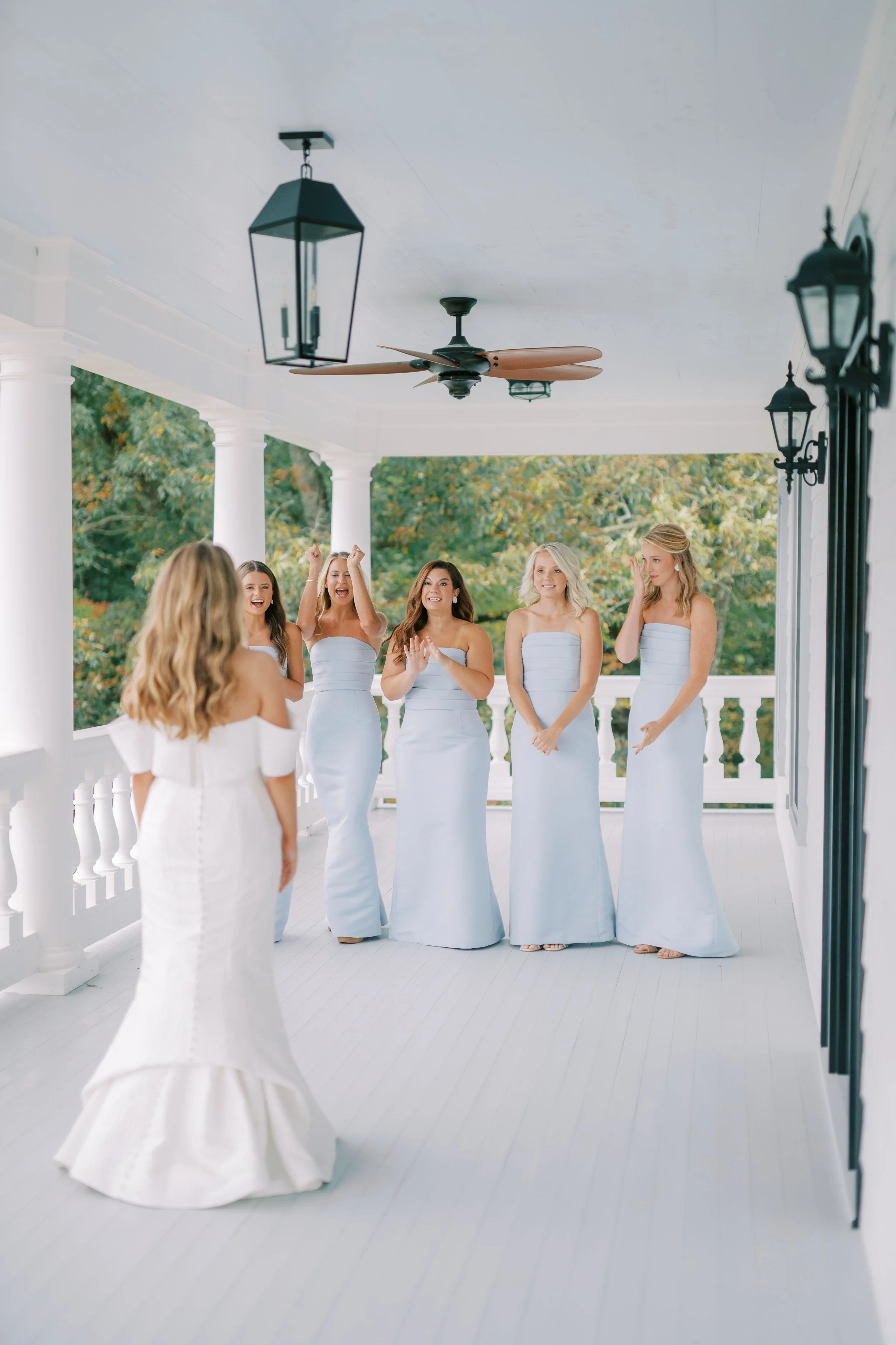 Bride with bridesmaids in matching light blue dresses on the porch