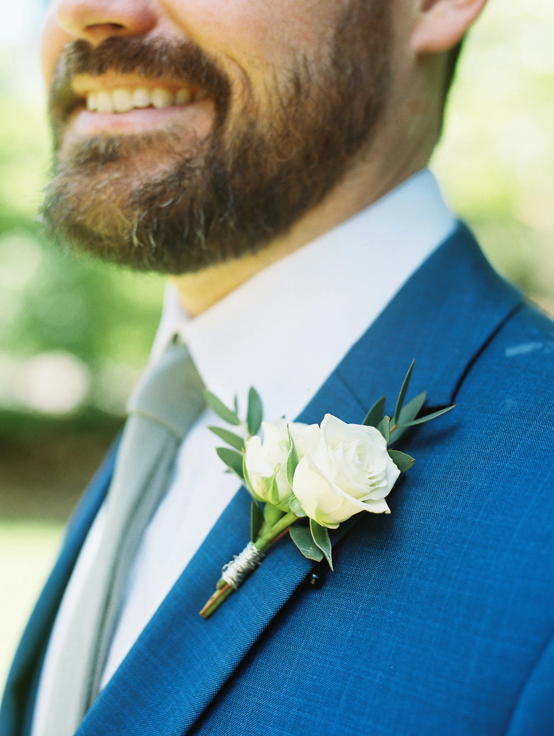 Close-up of the groom's white rose boutonniere detail