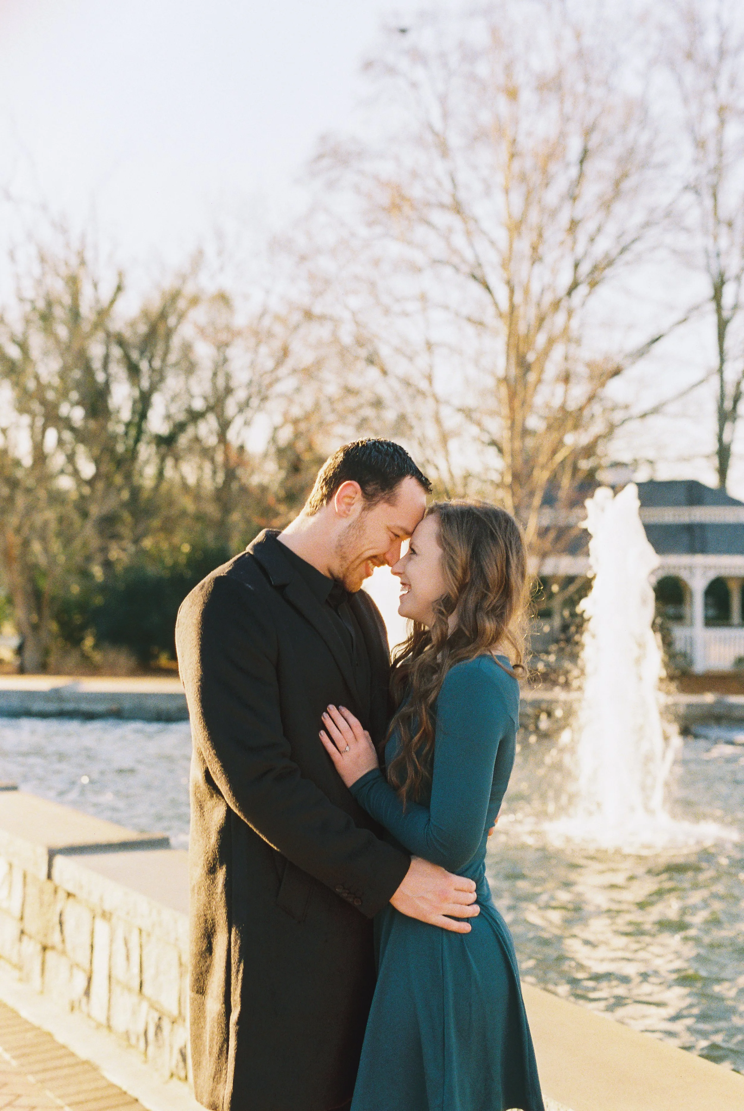 Conner and Maddie embrace forehead to forehead beside a park fountain in Dallas, Georgia.