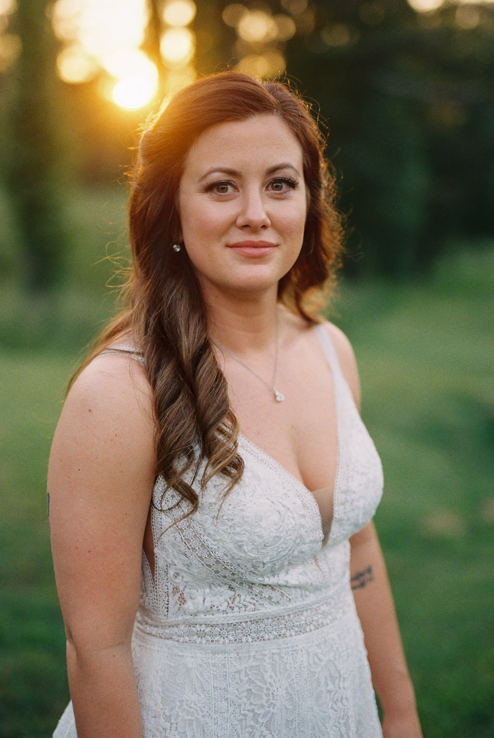 Solo portrait of the bride smiling softly, backlit by the setting sun with her hair styled in a side braid
