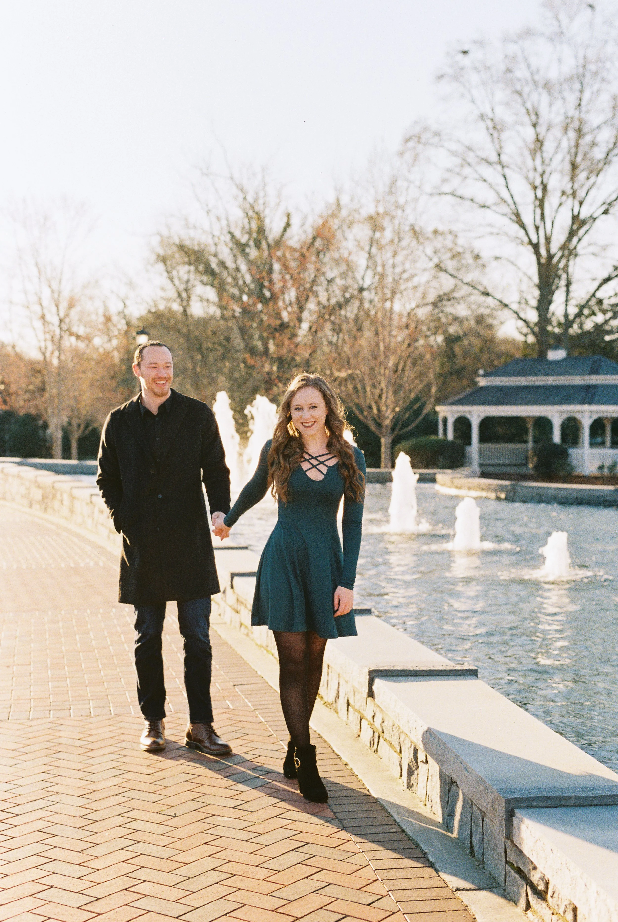 Conner and Maddie walk hand in hand along the path beside the park fountain in Dallas, Georgia.