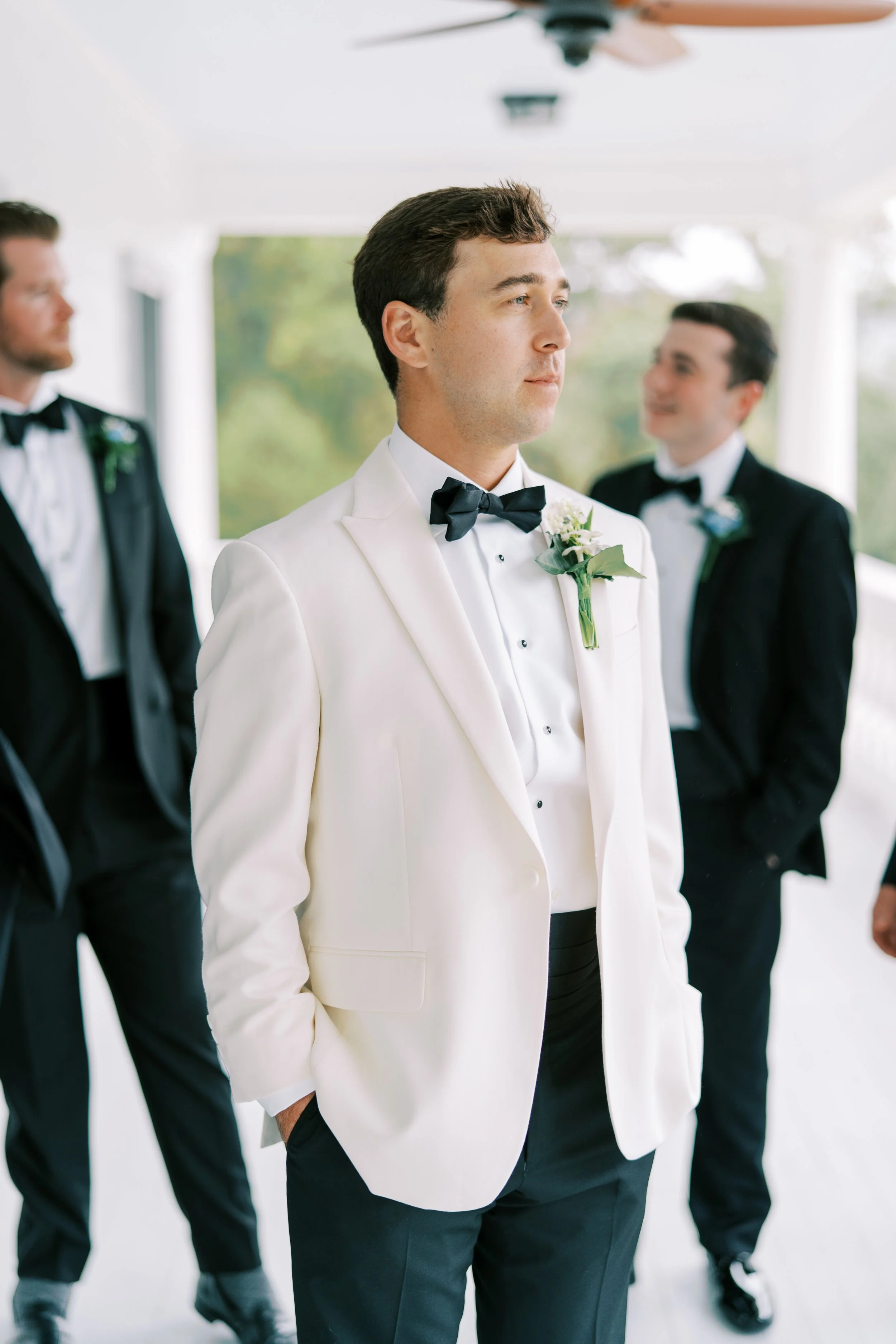 Groom standing on the porch with a groomsman in the background