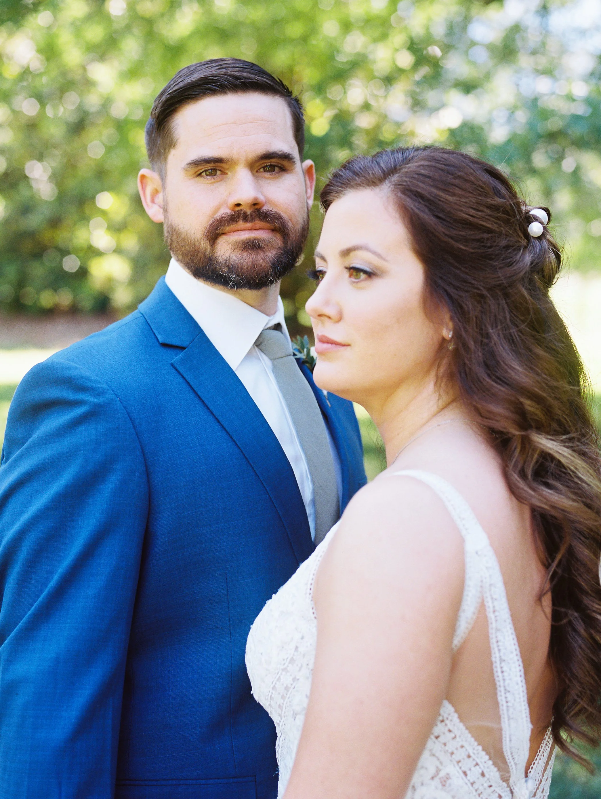 Close-up portrait of the bride and groom standing close together, both gazing off to the side