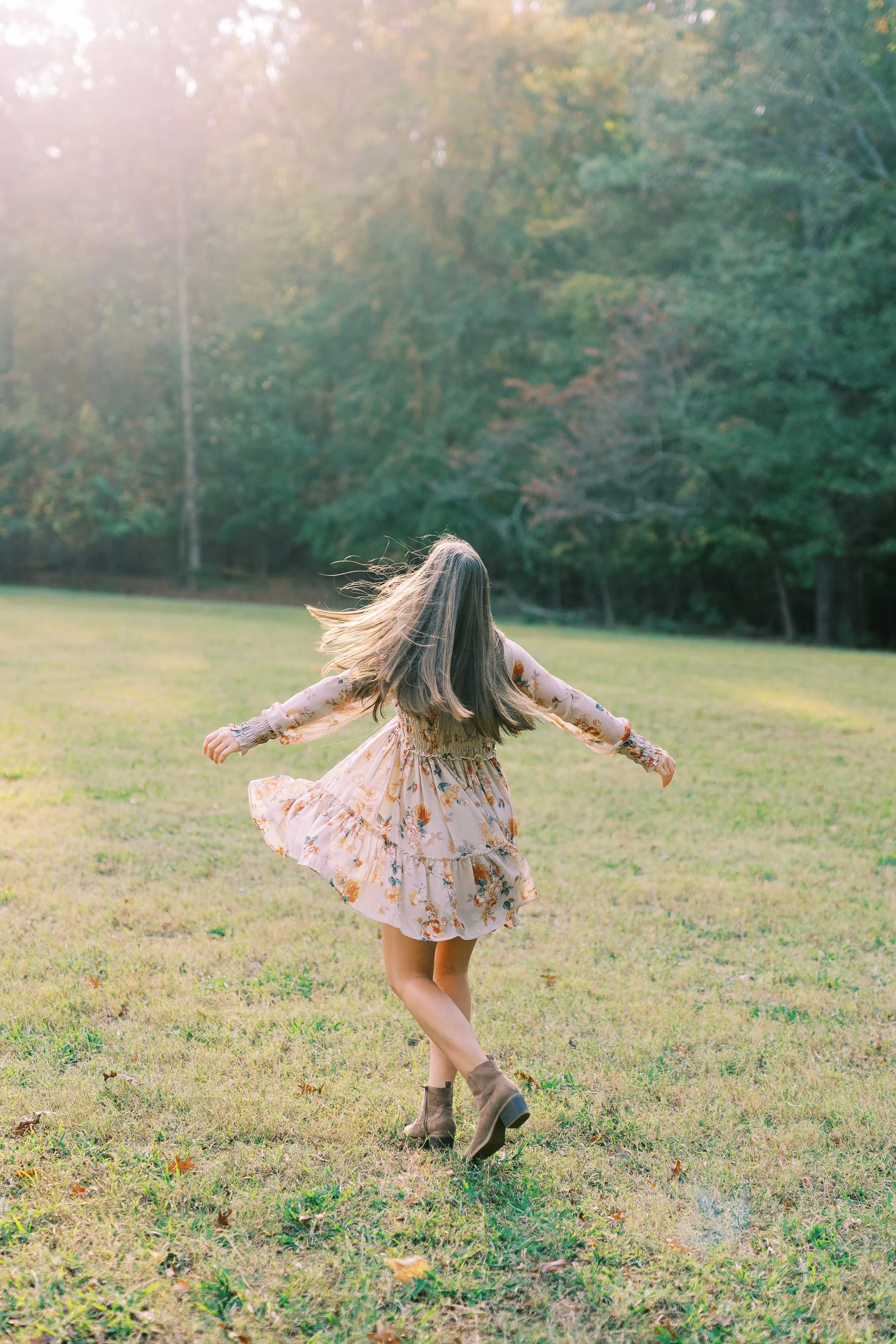 Senior portrait of Hannah twirling in a floral dress on the grass at Kennesaw Mountain Battlefield Park in Kennesaw, Georgia