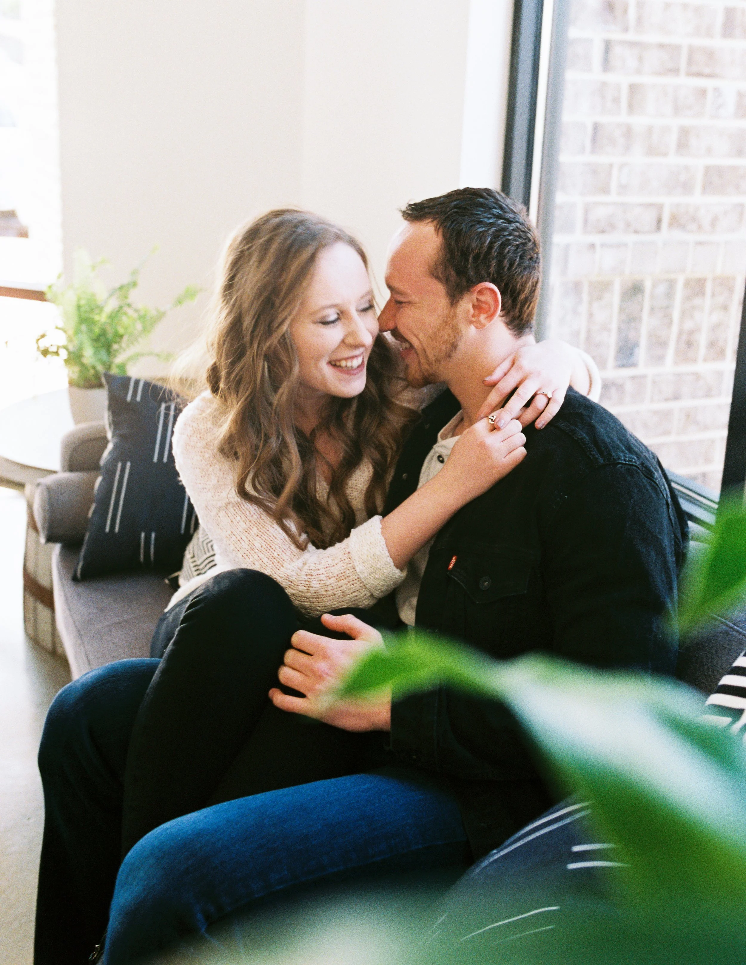 Conner and Maddie sit close together laughing on a couch inside a Dallas, Georgia coffee shop.