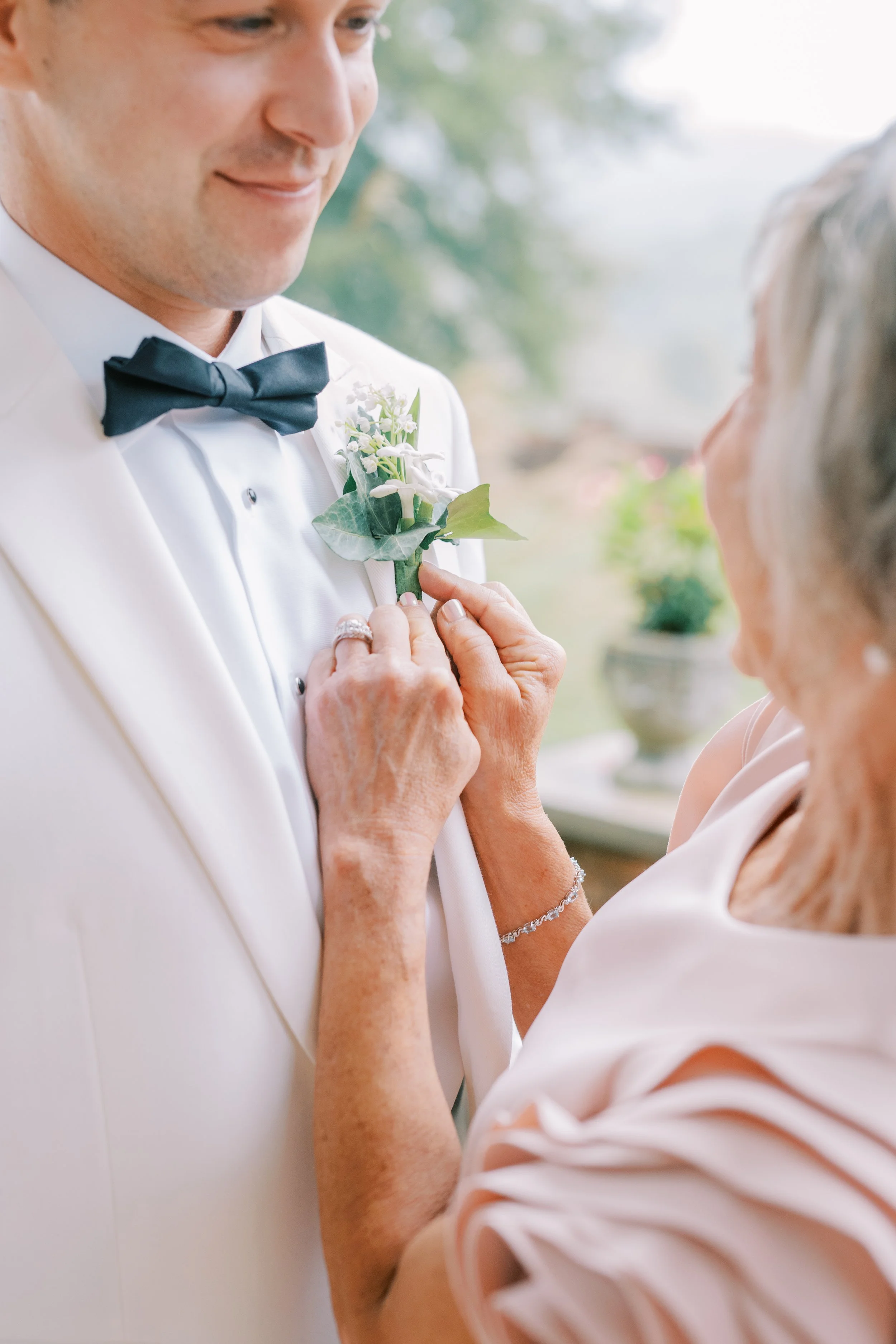 Groom's mother pinning his boutonniere before the ceremony