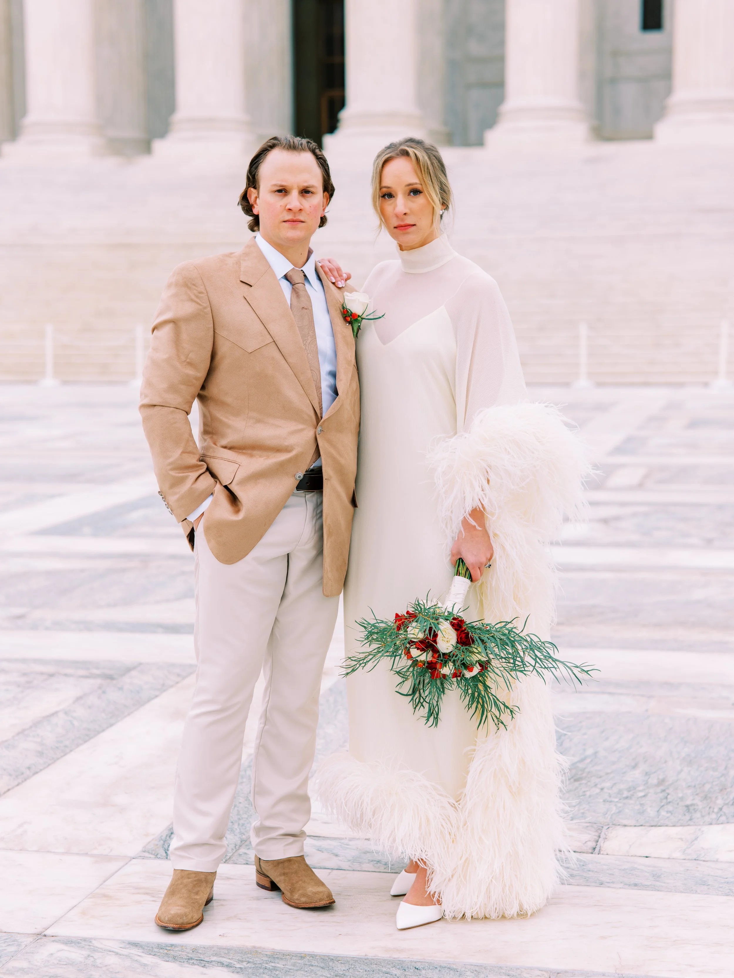 Bride and groom standing together on a Washington DC plaza, bride in a feathered gown