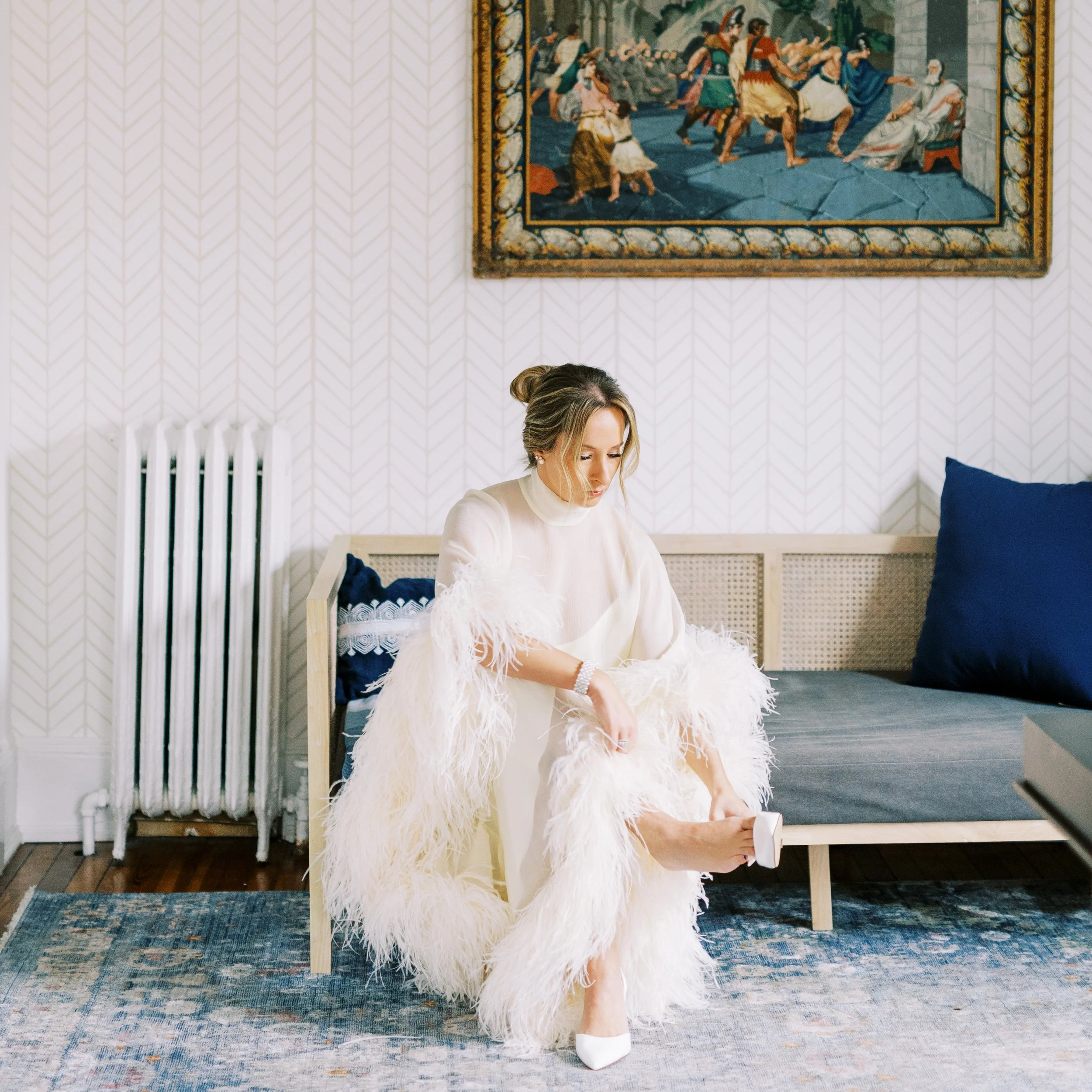 Bride seated on a bench adjusting her dress while getting ready