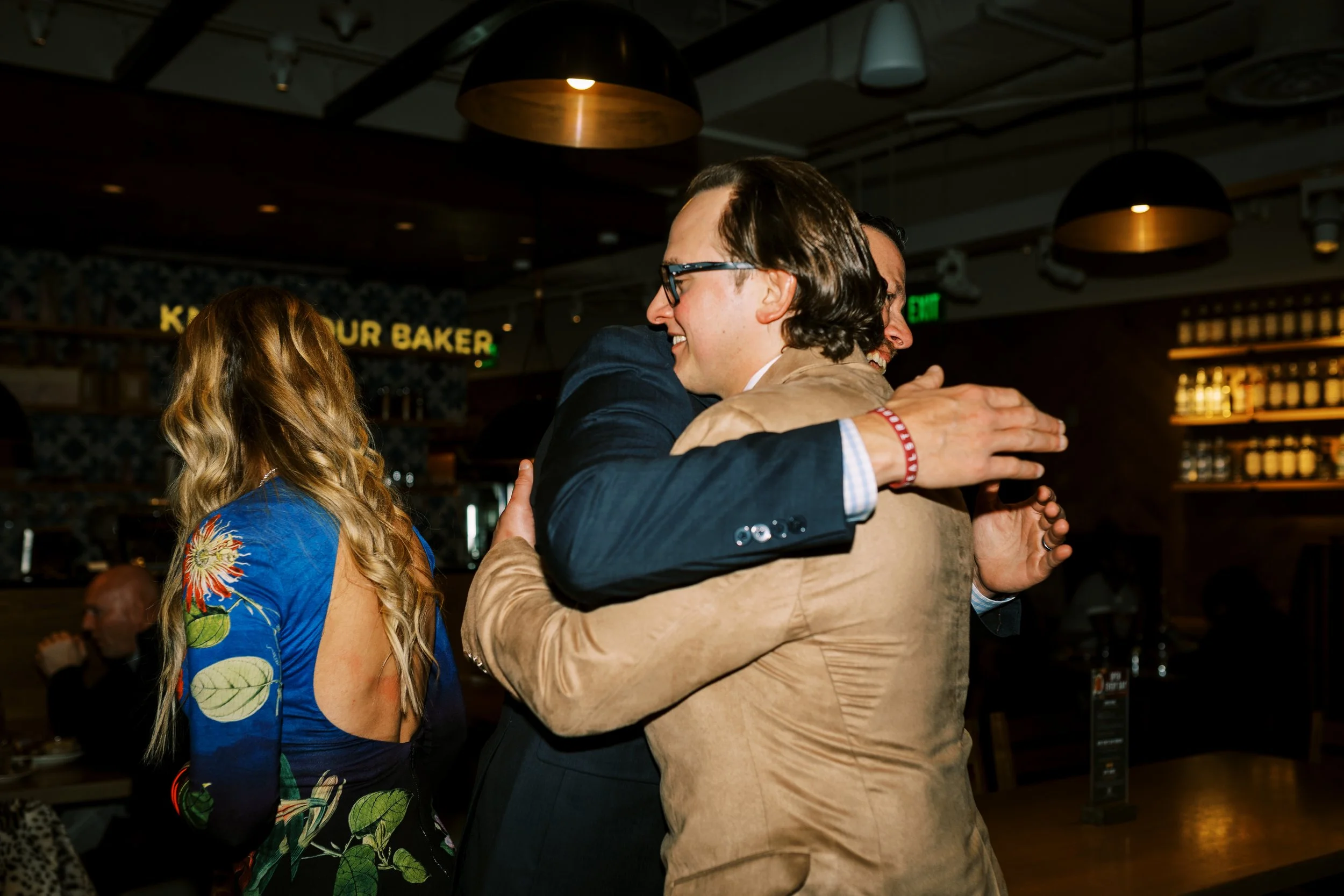 Groom embracing a guest at the restaurant bar during the celebration