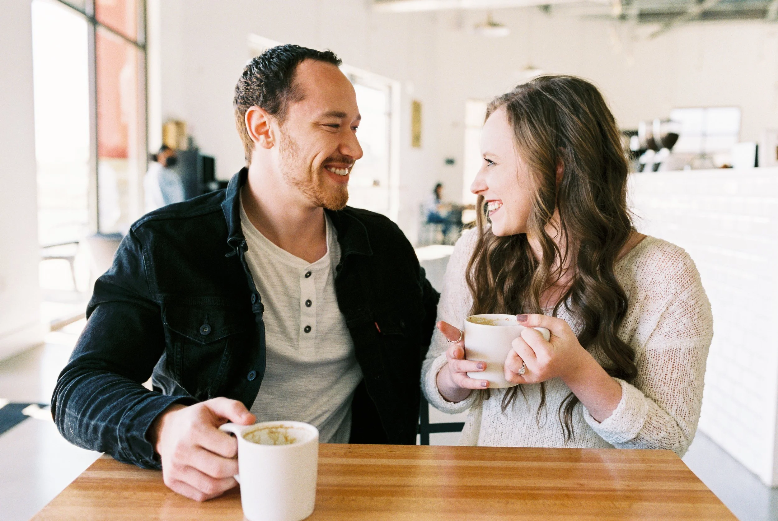 Conner and Maddie laugh together over coffee mugs at their table in a Dallas, Georgia coffee shop.