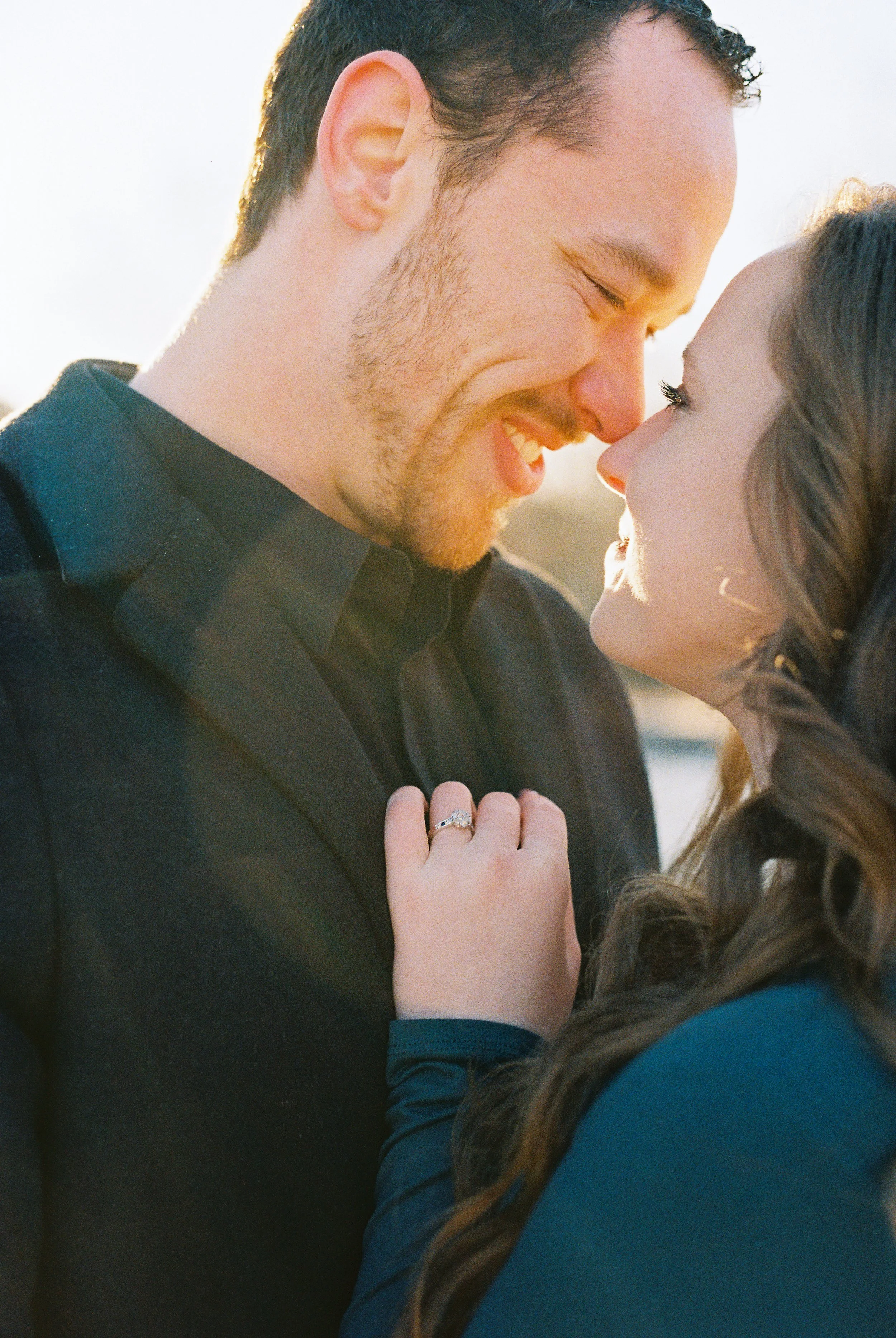 Conner smiles at Maddie with sun flare and her engagement ring visible on his shoulder during their Dallas, Georgia engagement session.