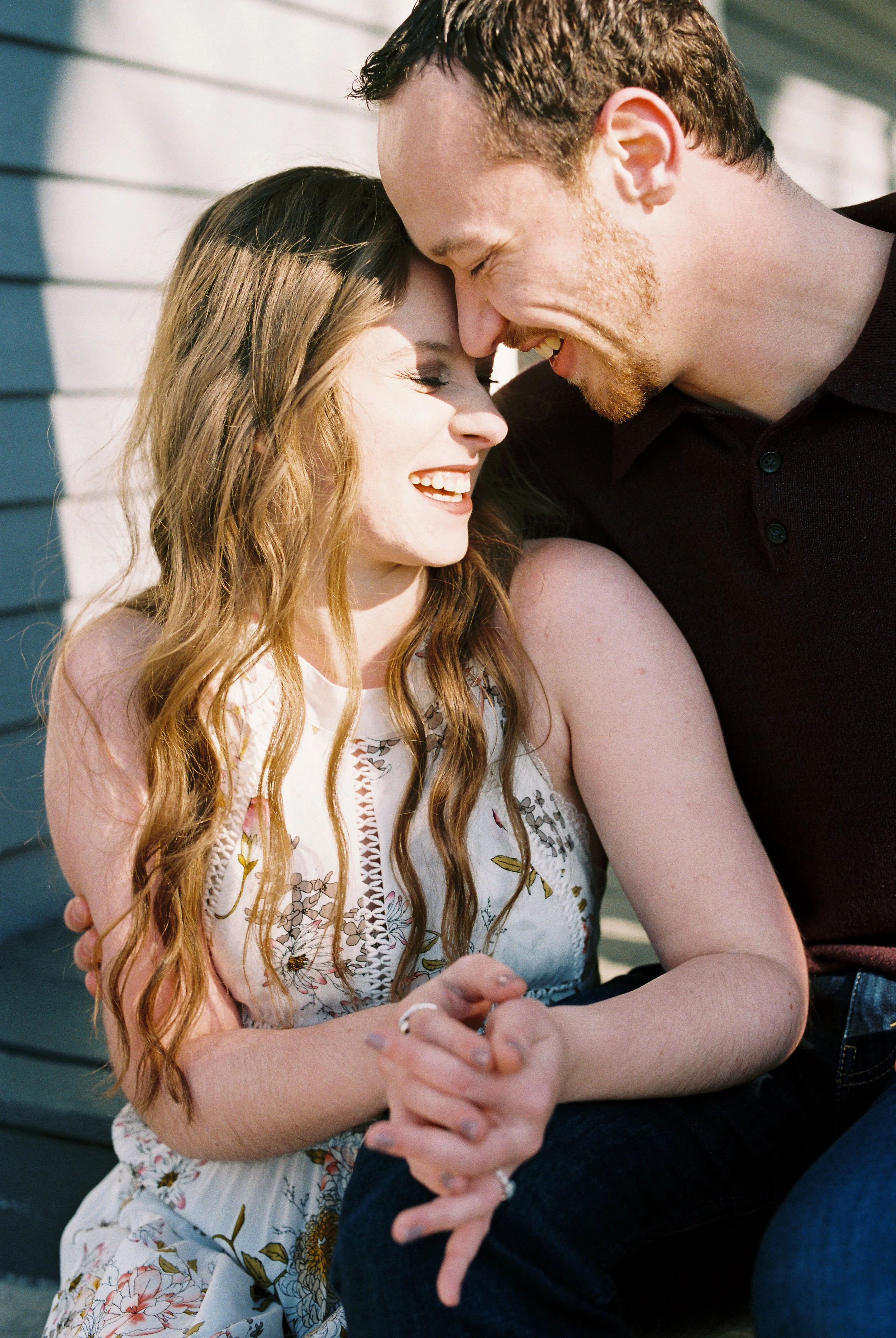 Conner and Maddie hold hands and laugh together on the porch steps of a historic home in Dallas, Georgia.