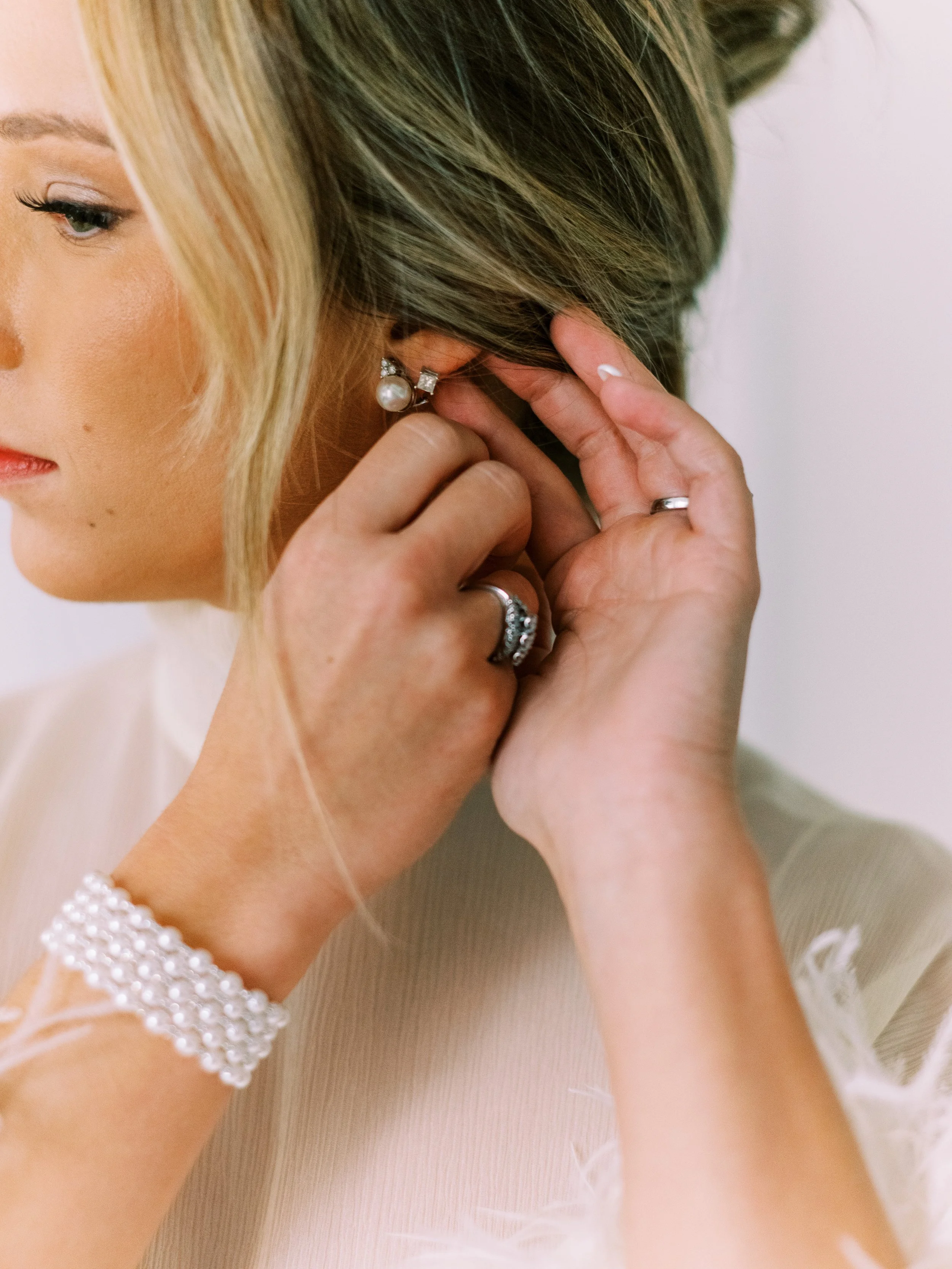 Close-up of the bride putting on her earring while getting ready