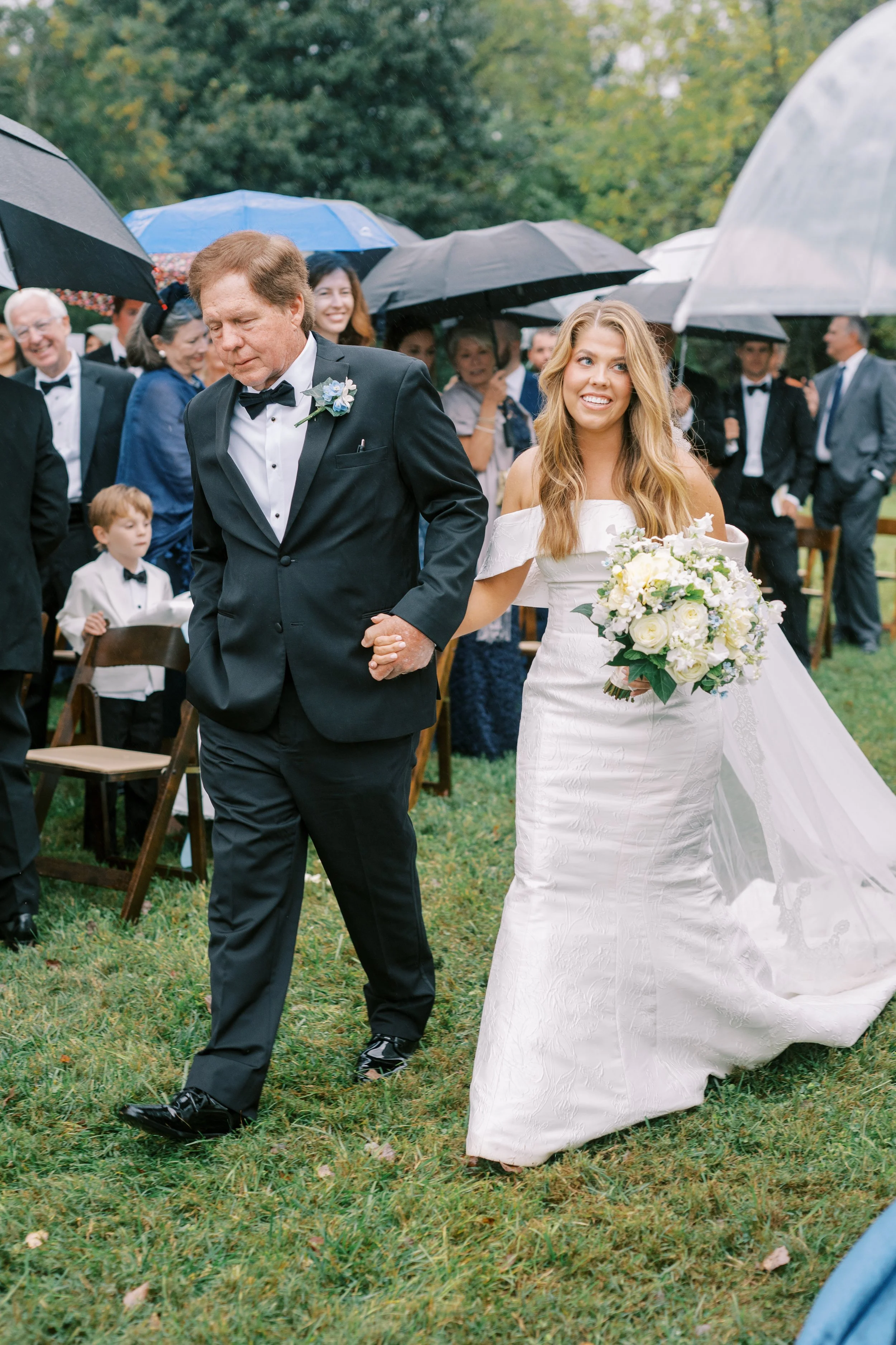 Bride walking down the aisle with her father under an umbrella