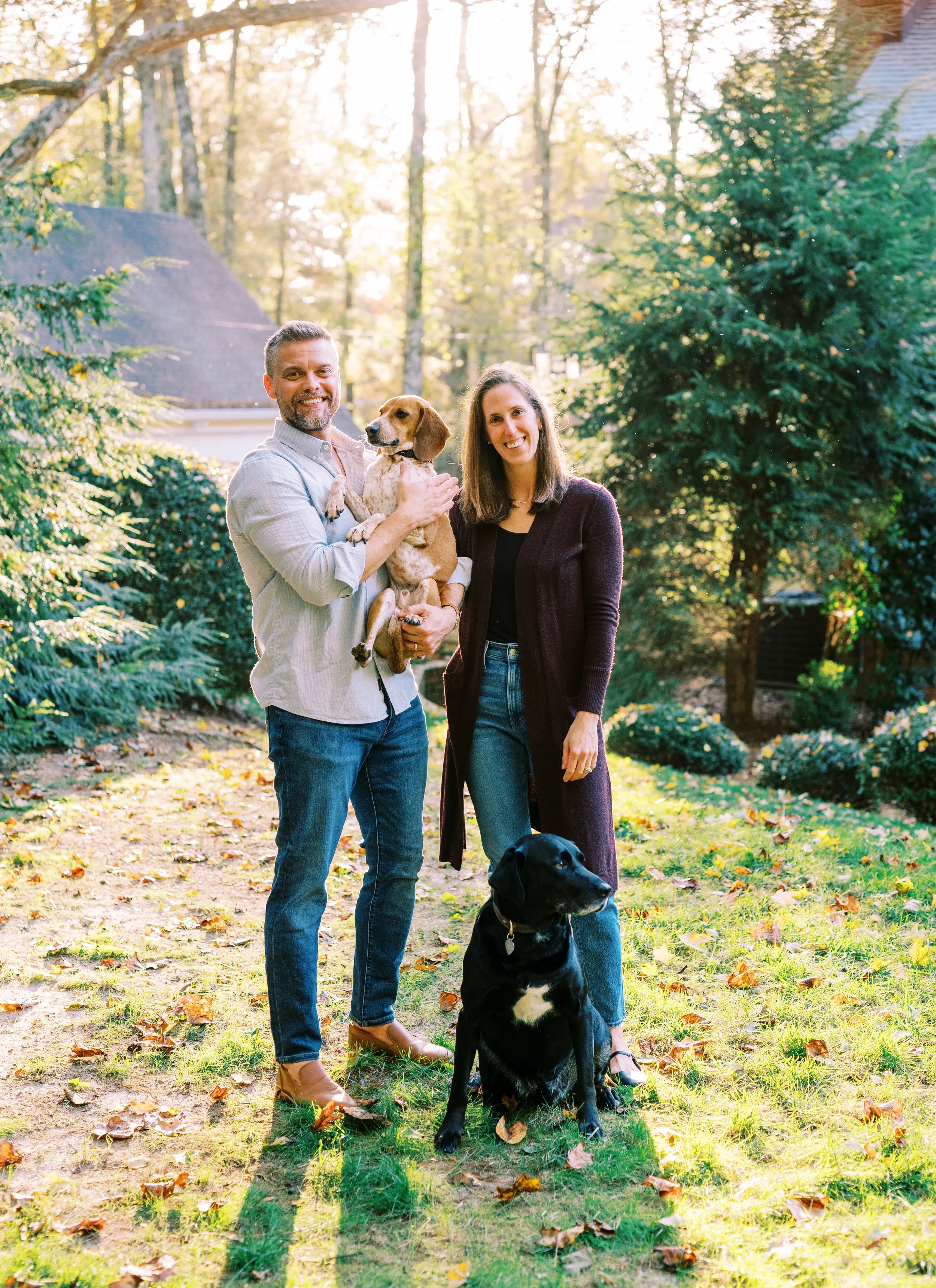Holly and Chris with their child and rescue dog standing together in their wooded yard in Dunwoody, Georgia