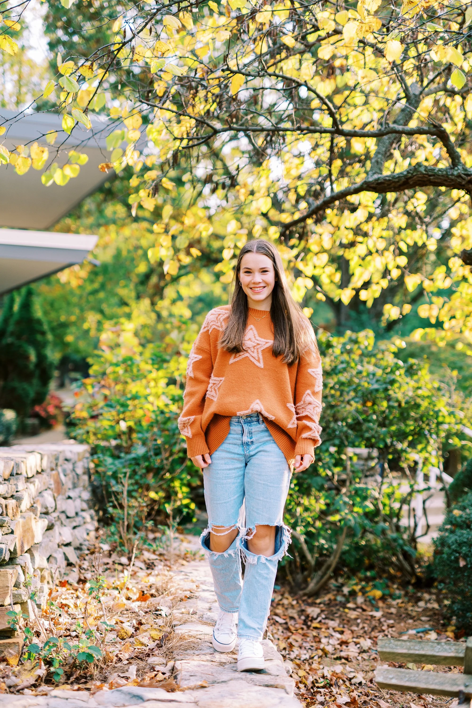Senior portrait of Hannah standing among fall foliage in an orange sweater at Kennesaw Mountain Battlefield Park in Kennesaw, Georgia