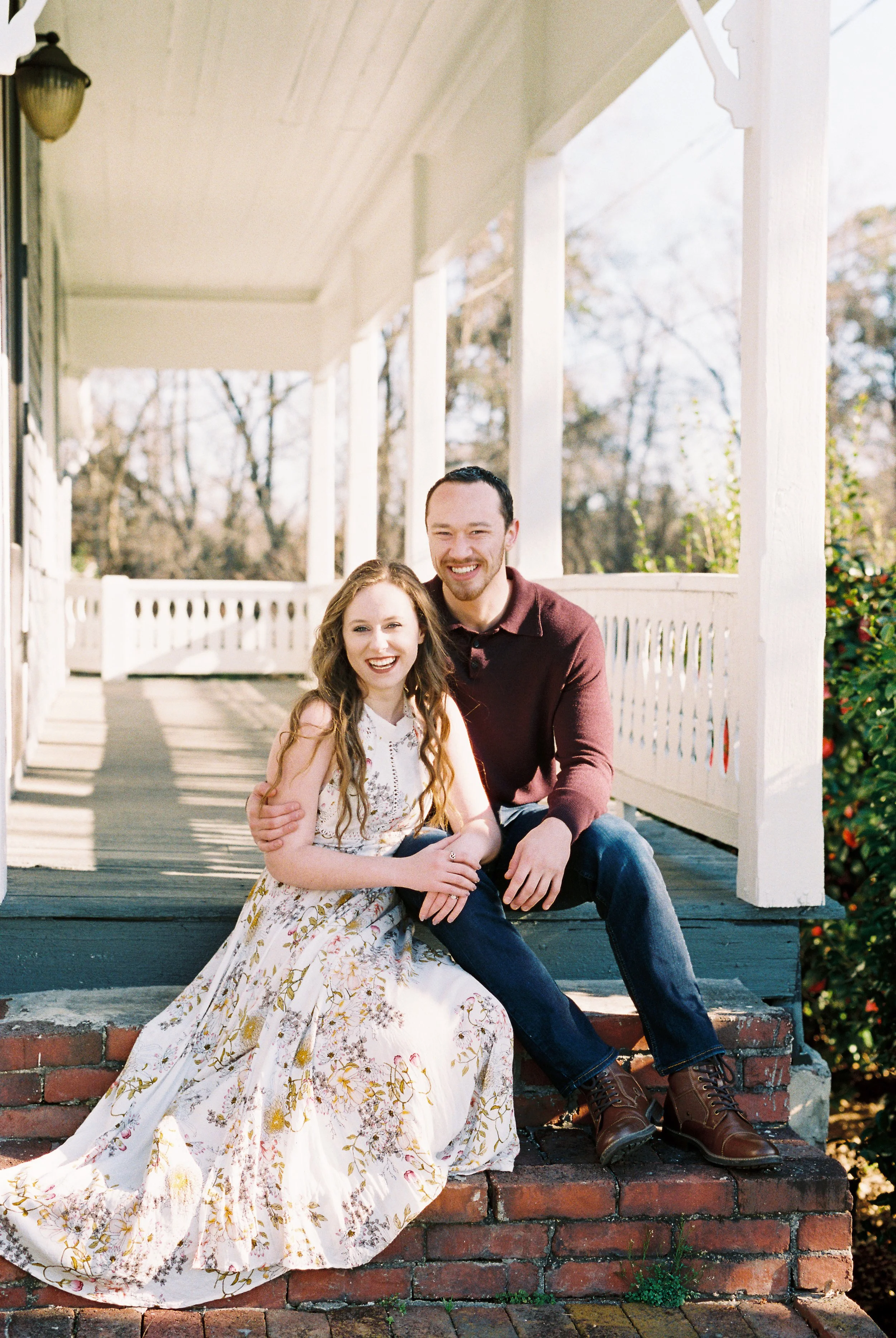 Conner and Maddie smile at the camera while seated on the porch steps of a historic home in Dallas, Georgia.