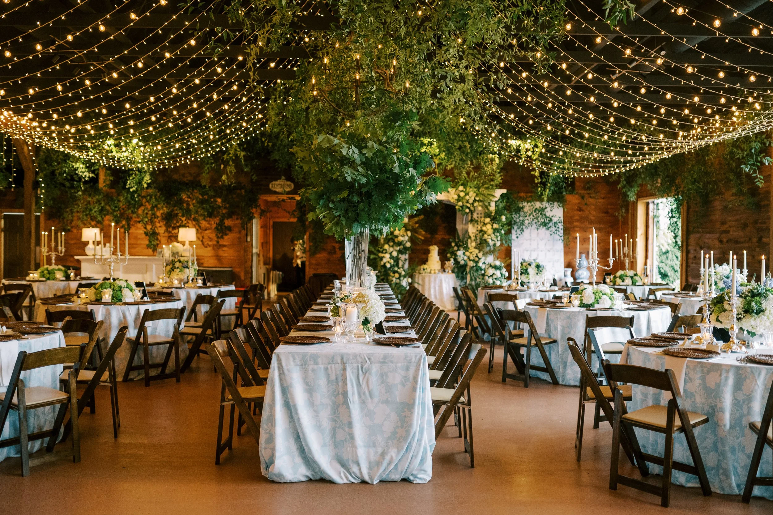 Wide view of reception venue interior with long tables and string lights