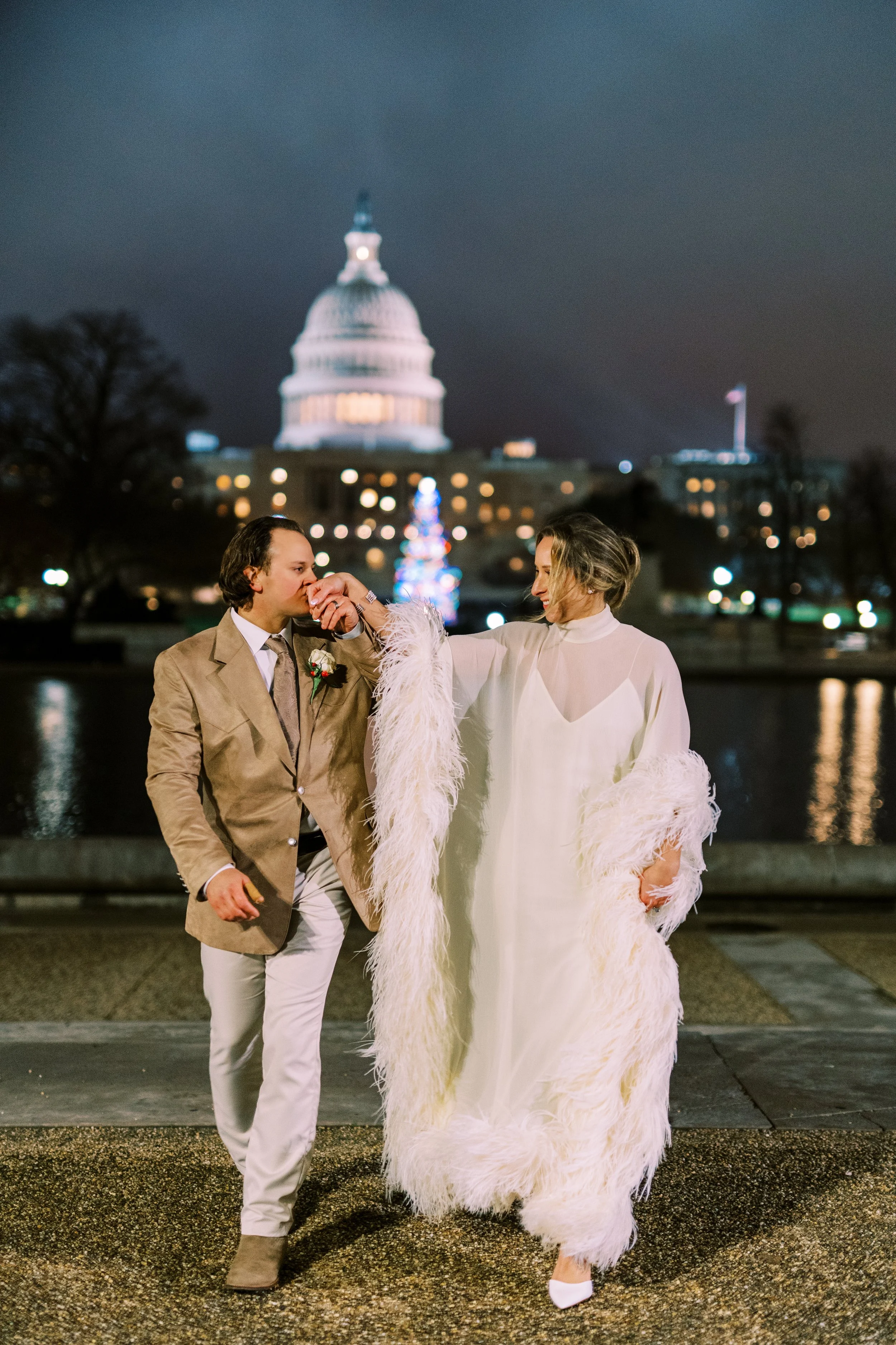 Bride and groom walking together at night with the illuminated Capitol dome in the background