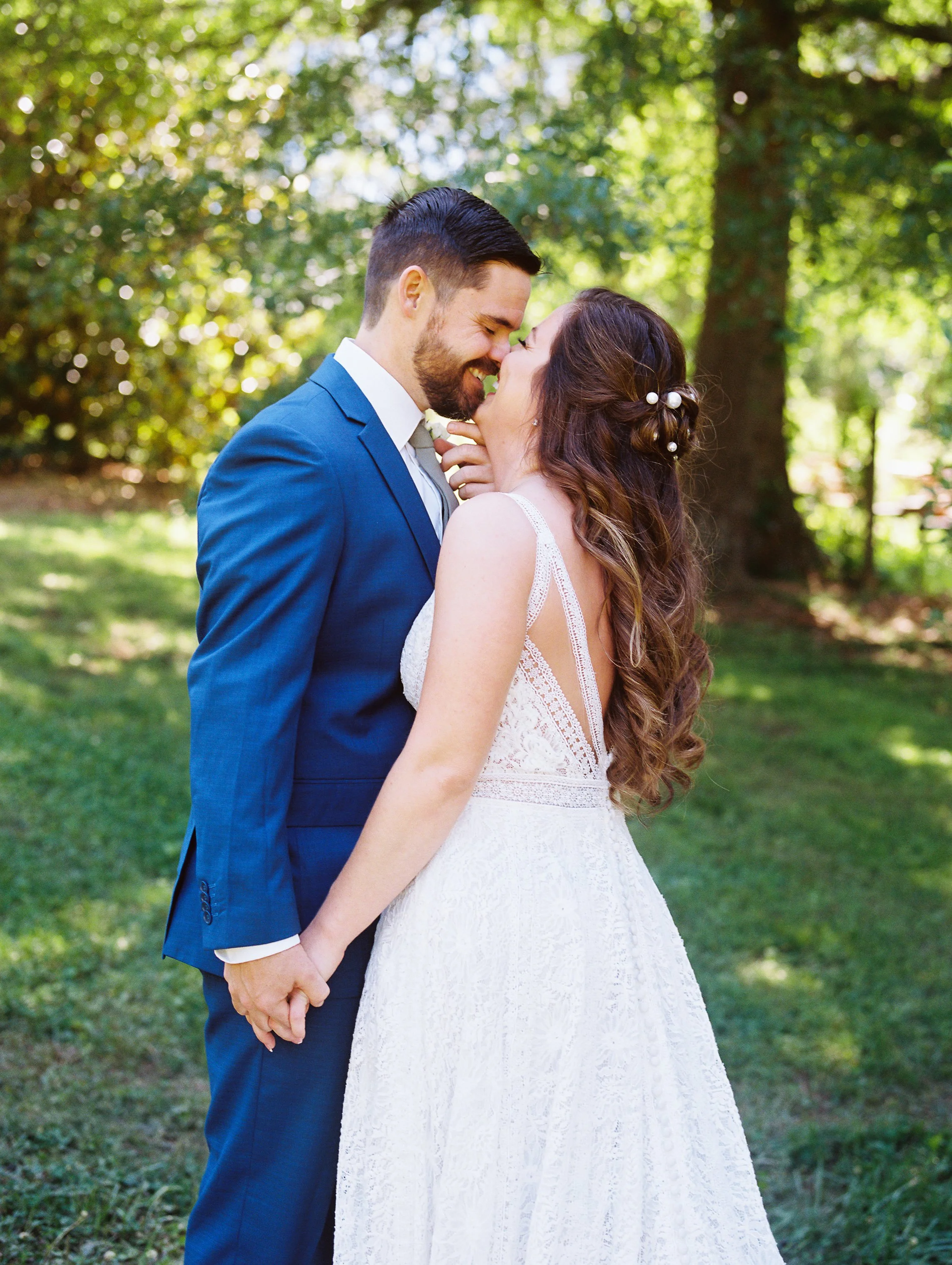 Bride and groom with foreheads touching in a wooded garden clearing