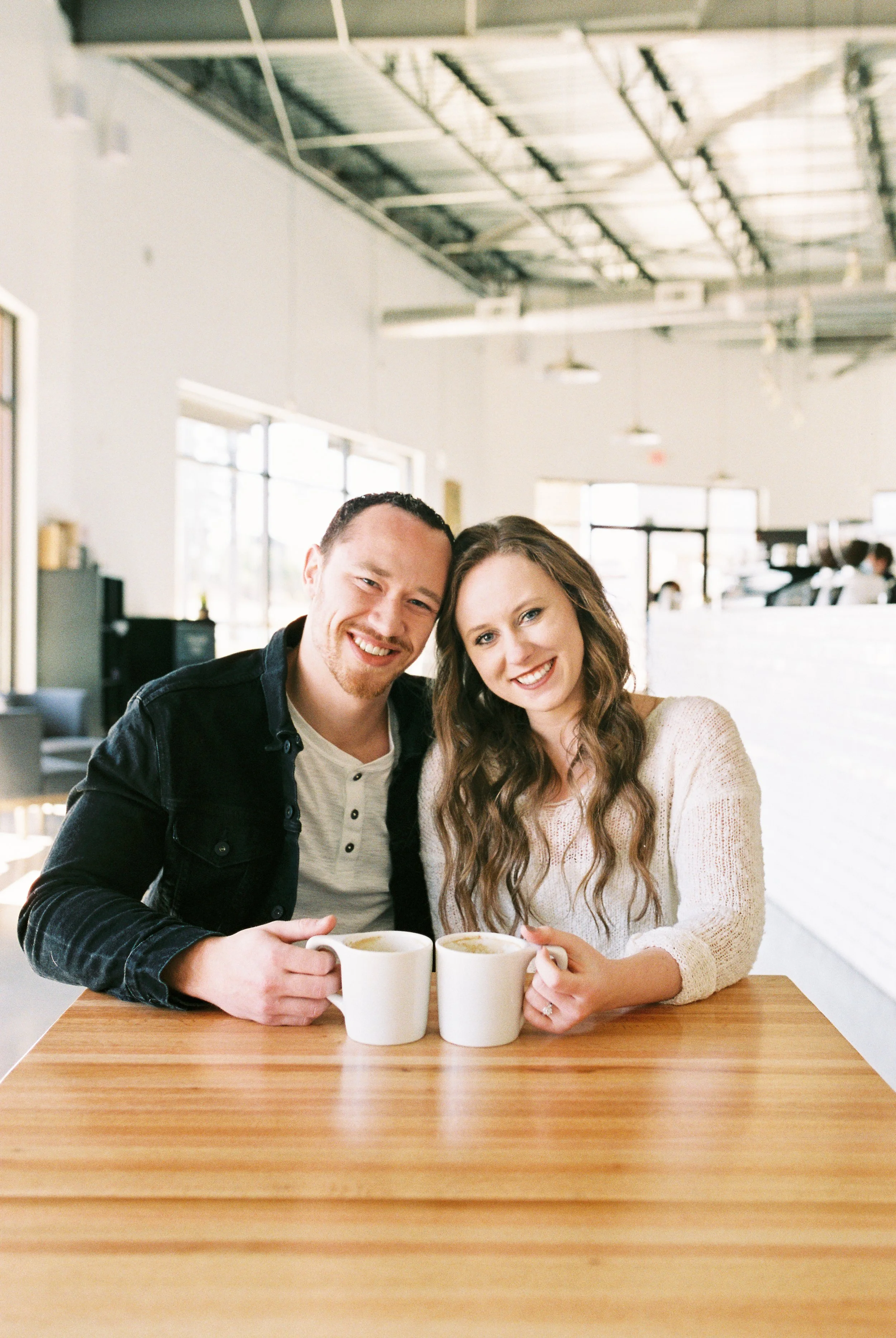 Conner and Maddie smile at the camera with their coffee mugs at a table in a Dallas, Georgia coffee shop.