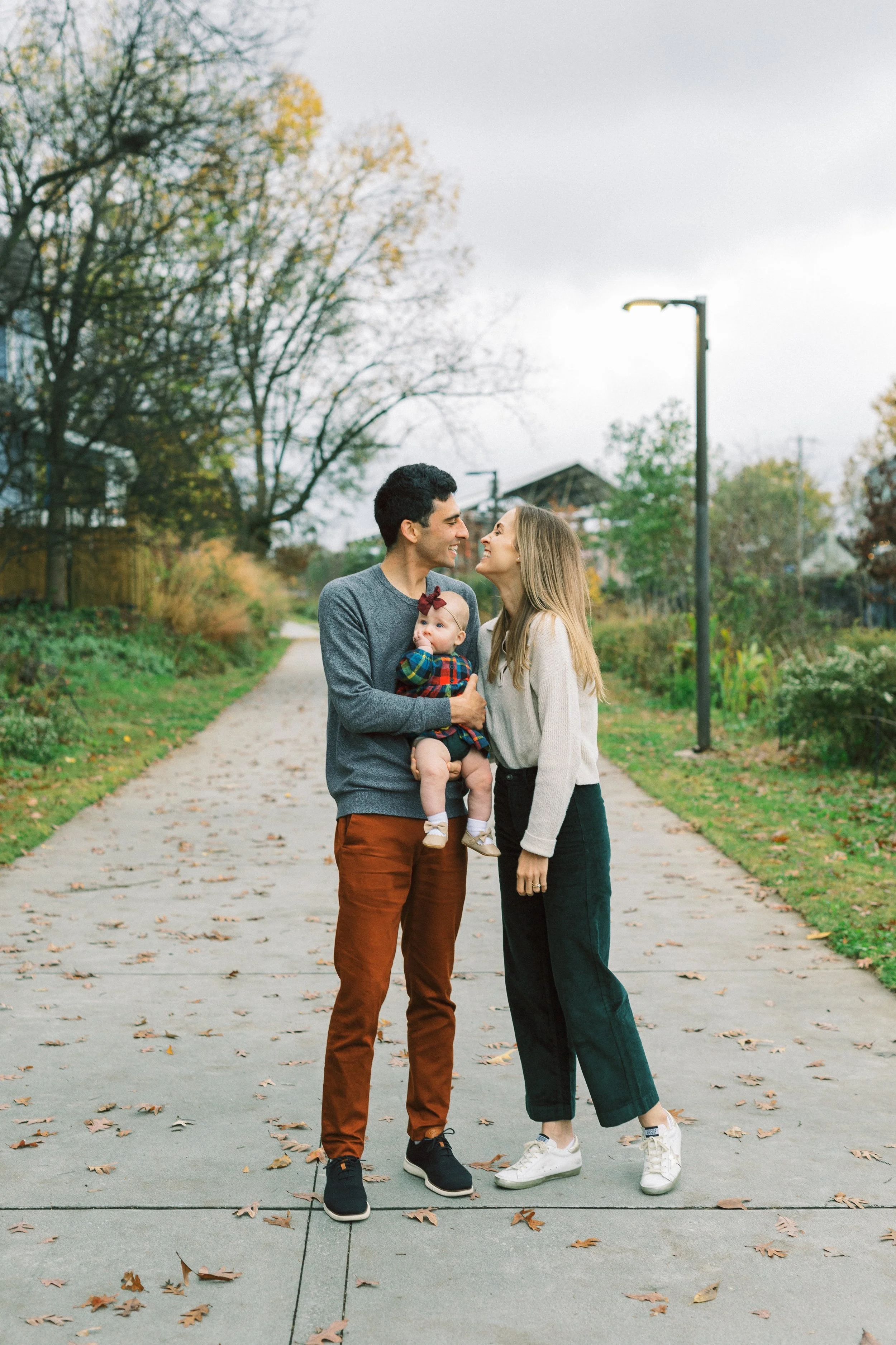Dad holding baby girl in plaid outfit while parents laugh together, Reynoldstown, Atlanta, Georgia