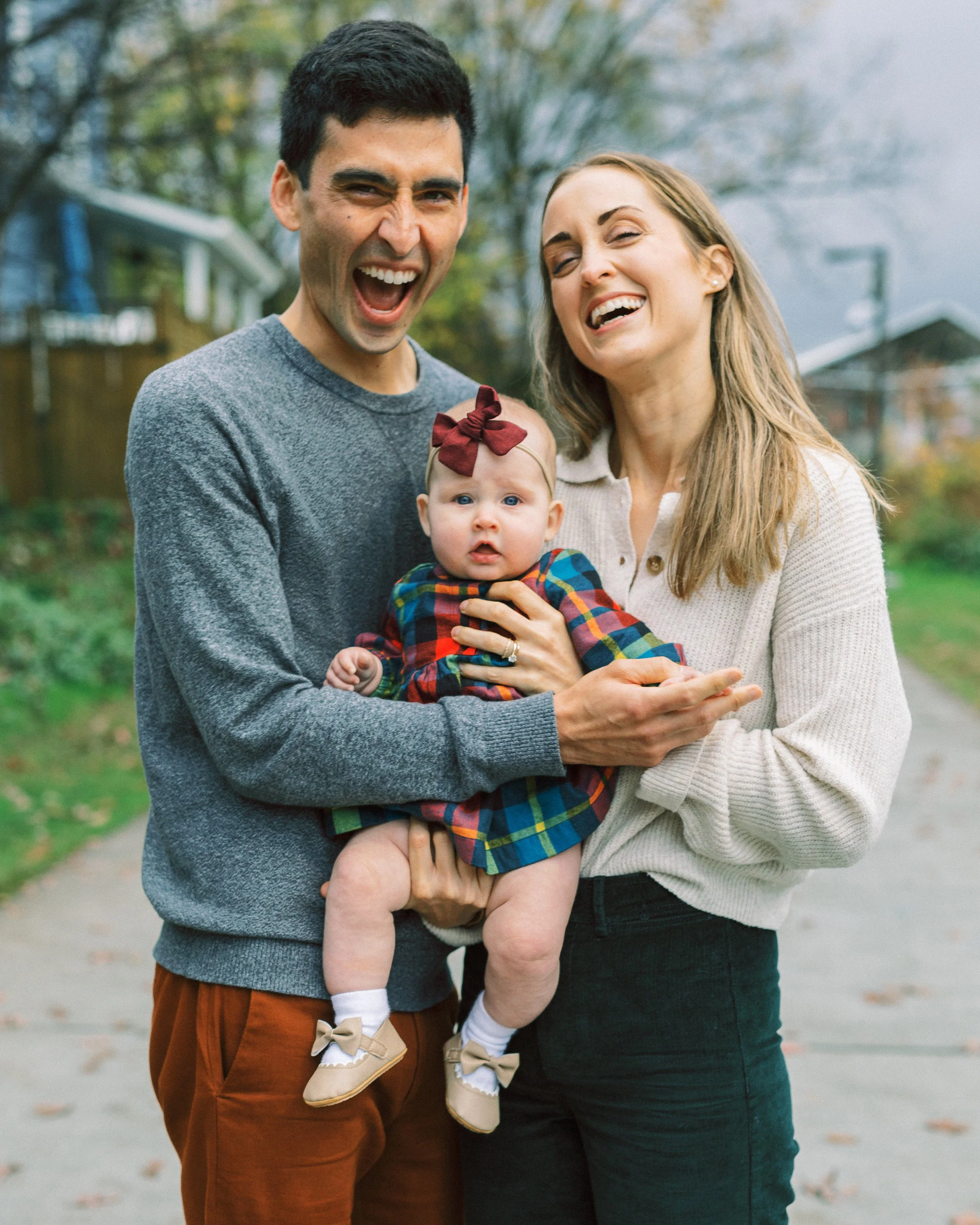Dad kissing mom's head while she smiles, holding their baby girl on a neighborhood path, Reynoldstown, Atlanta, Georgia