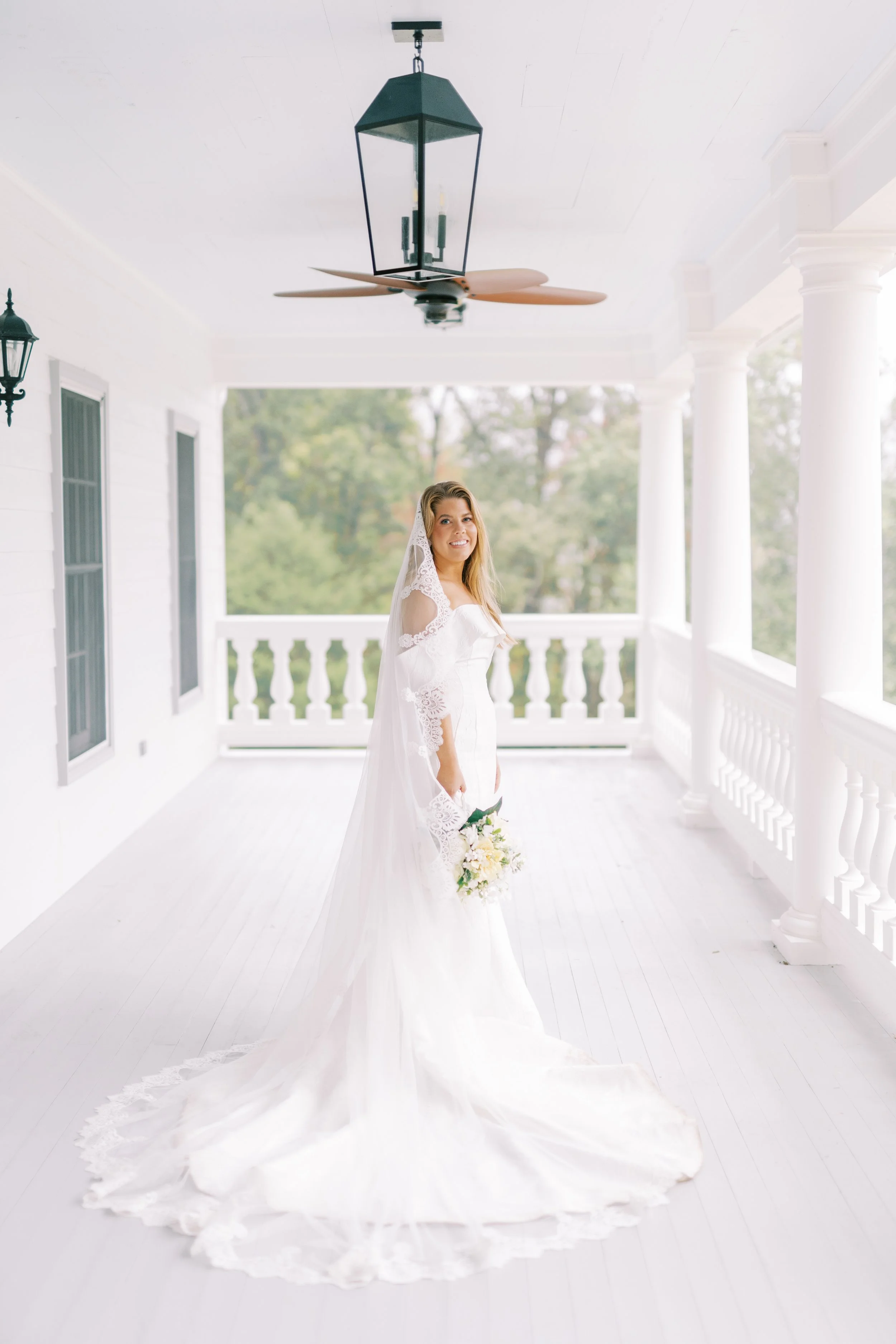 Bride standing alone in the covered breezeway of the plantation house