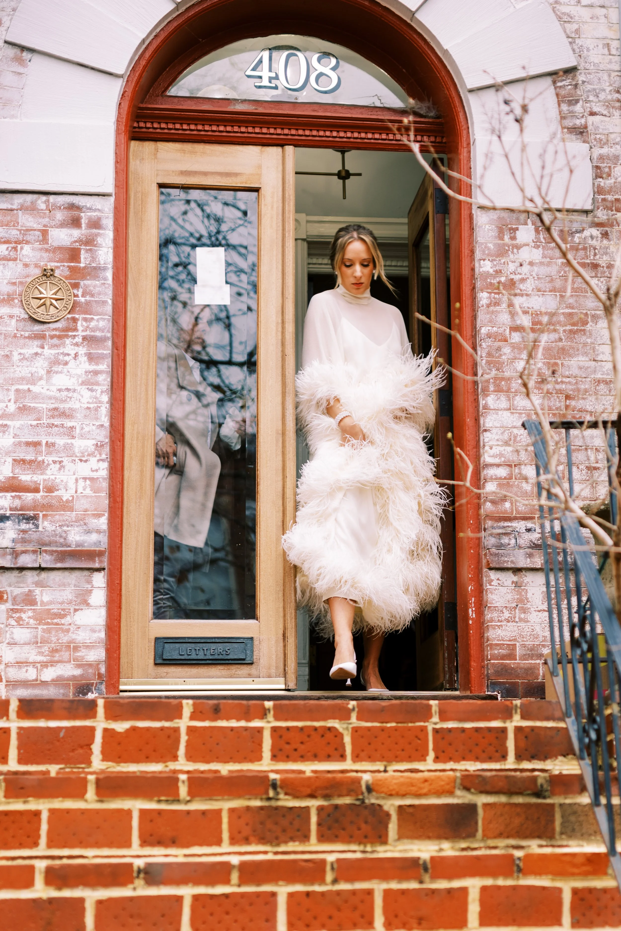 Bride in a fur coat standing in a brick building doorway in Washington DC